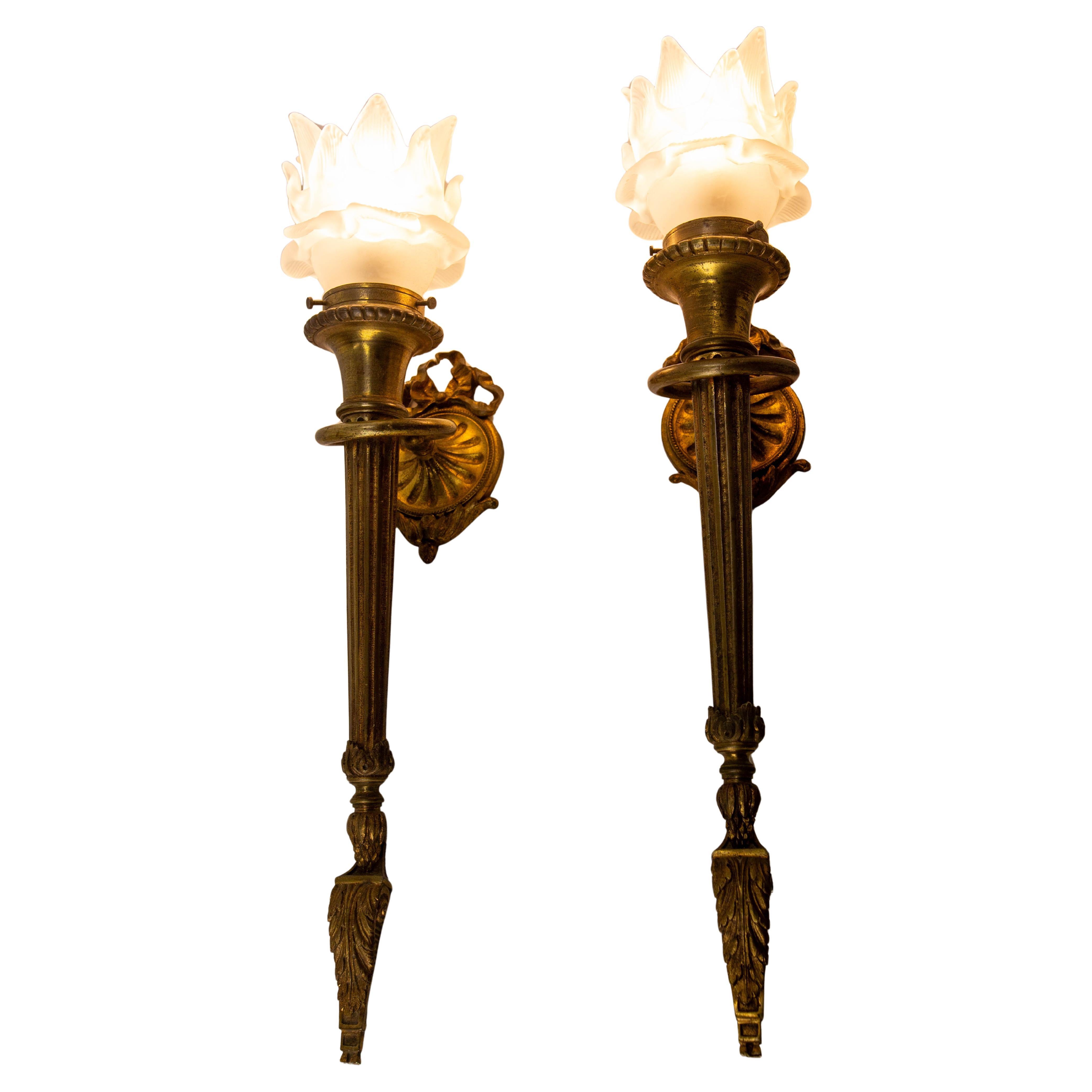 Paire d'appliques murales en laiton massif et verre tulipe glacé.

Ces appliques en forme de torche donneront à votre intérieur un aspect classique. Ils sont constitués d'un anneau dans lequel on aurait glissé une torche. La forme des tulipes