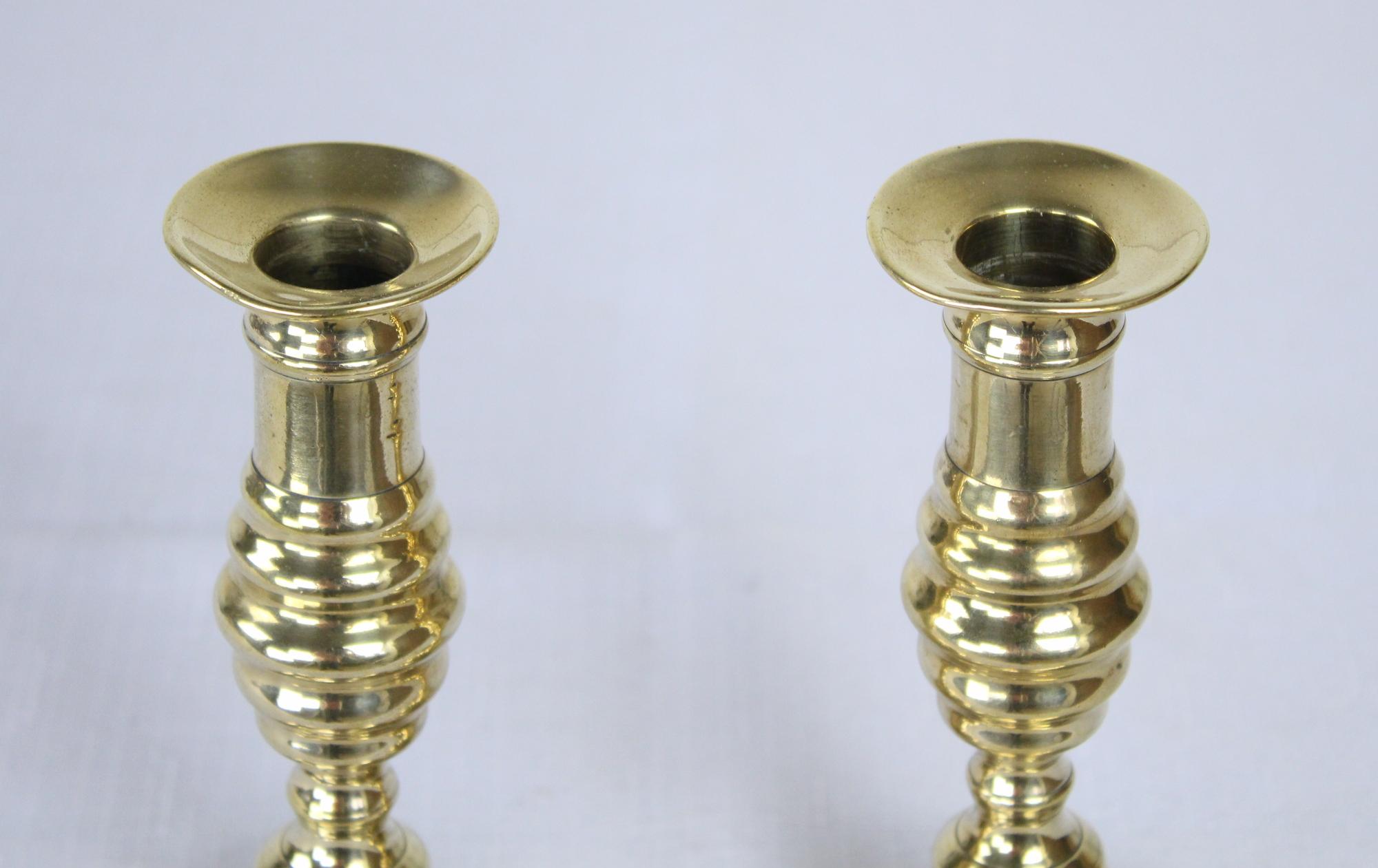 A pair of antique English brass candlesticks, from the Georgian period. Note that they need to be properly positioned, facing front, to look straight. This is a peculiarity on some Georgian candlesticks that were going onto a mantle and would tilt