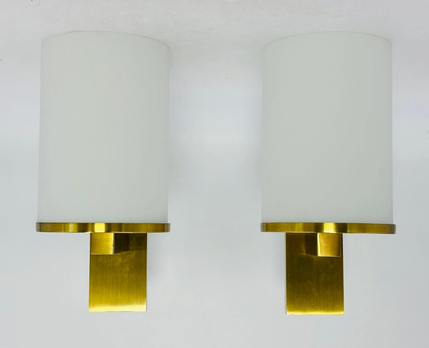 Rehaussez votre espace de vie avec cette paire d'appliques en laiton et verre, inspirée par les designs emblématiques de Jean Perzel dans la France des années 1960. Fabriquée avec précision et souci du détail, chaque applique est dotée d'un cadre en