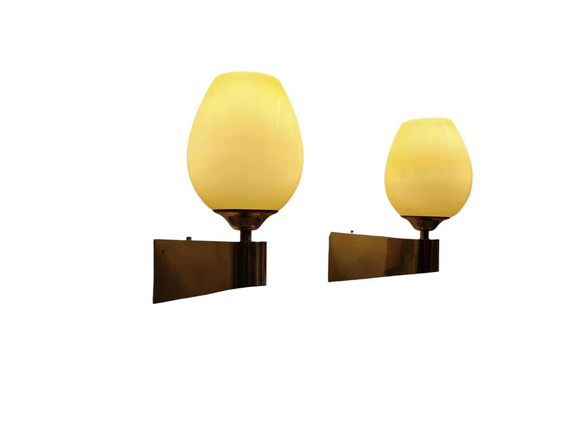 A nice pair of wall lamps in full brass, made by Itsu in Finland in the 1950s. Model EY 49. 
The lamps are minimalistic with a cubic design softened by curves and crown with a hand blown glass shade. Absolute beauties. Both lamps are in good