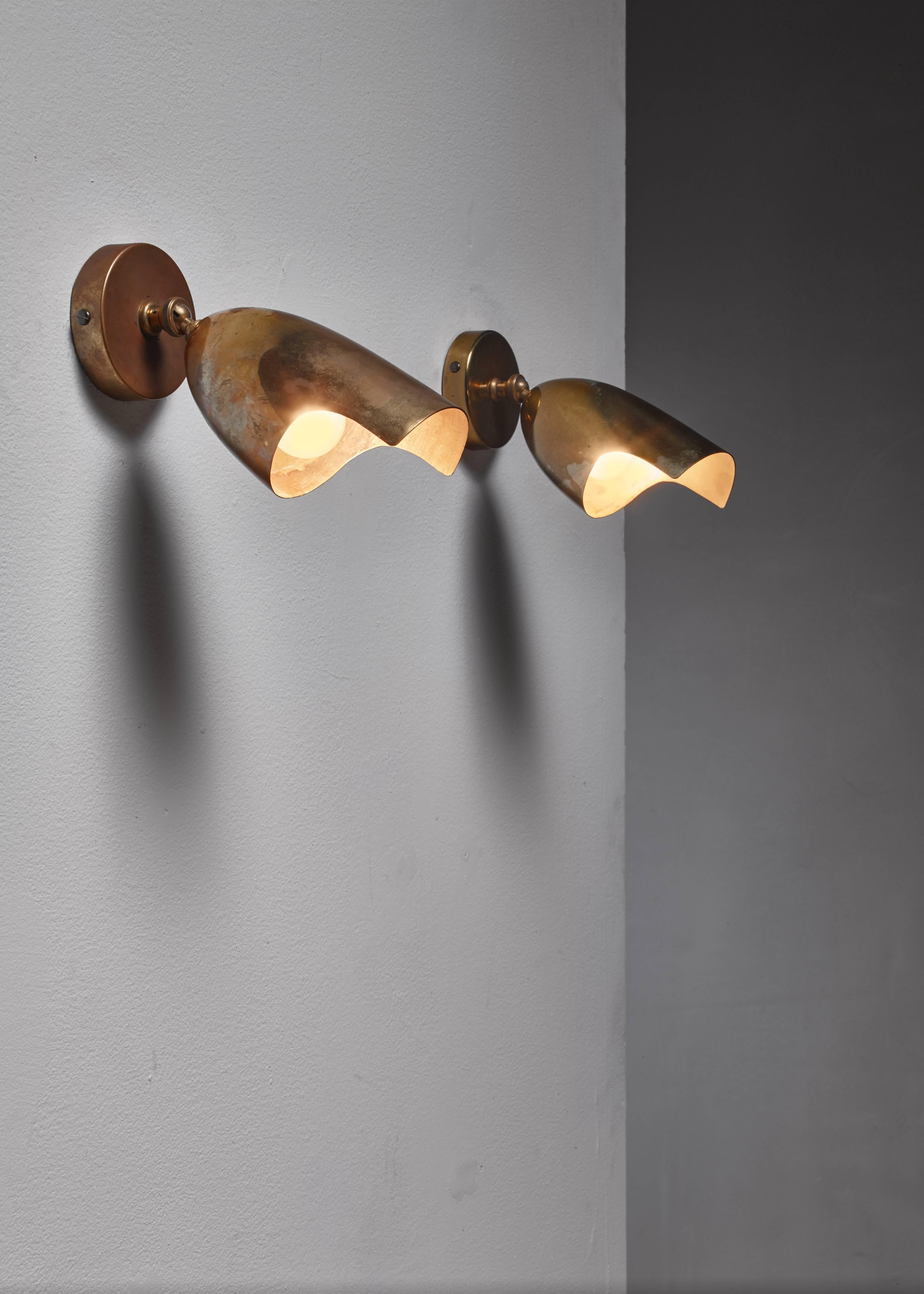 A set of two pivoting brass wall appliqués, labelled by Idman. They have a slight difference in patina. These lamps are from Idman's heyday of the 1950s, when the company produced lamps by the greatest Finnish designers, like Paavo Tynell and Mauri