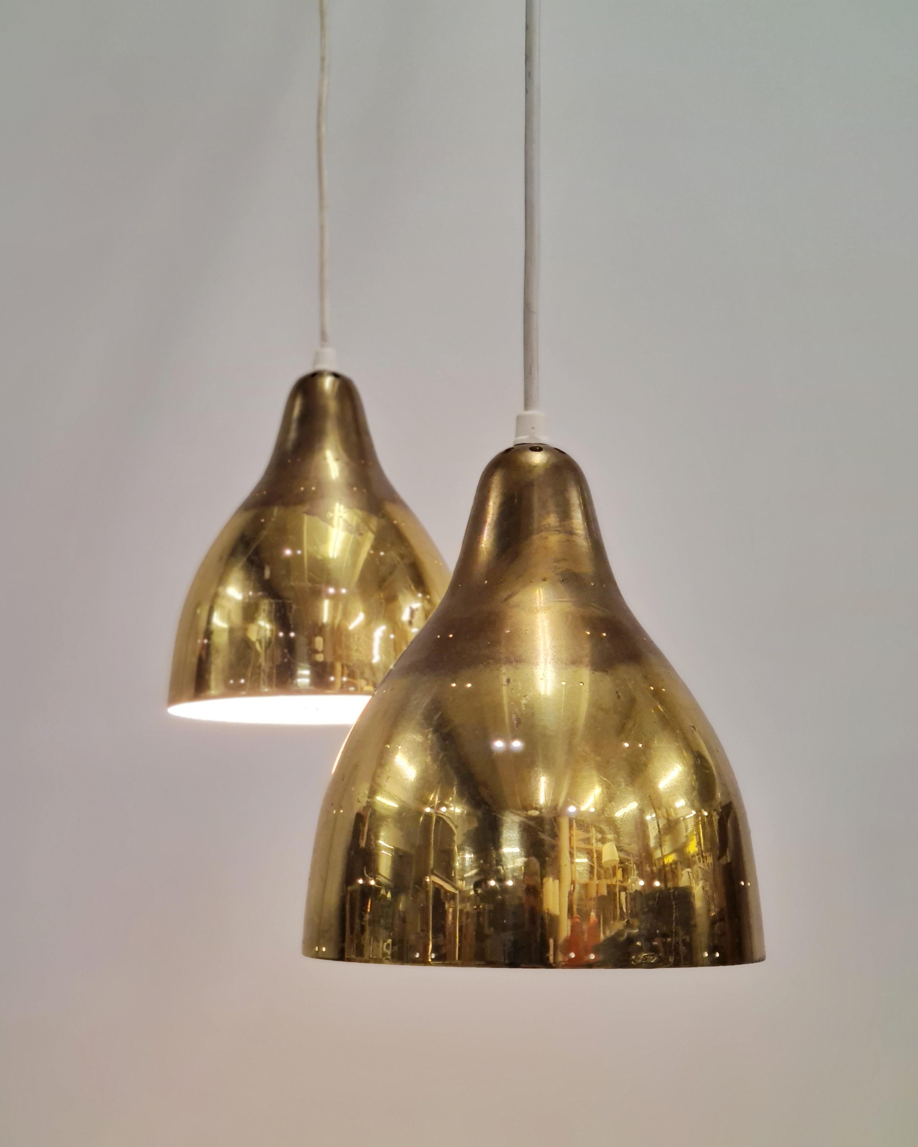 A beautiful pair of ceiling pendant lamps in full brass, made by Itsu in Finland in the 1950s. Model ER 84. 

The bell shaped brass shades are perforated with a two-dot pattern, are very beautiful and with their original patina. The lamps are small