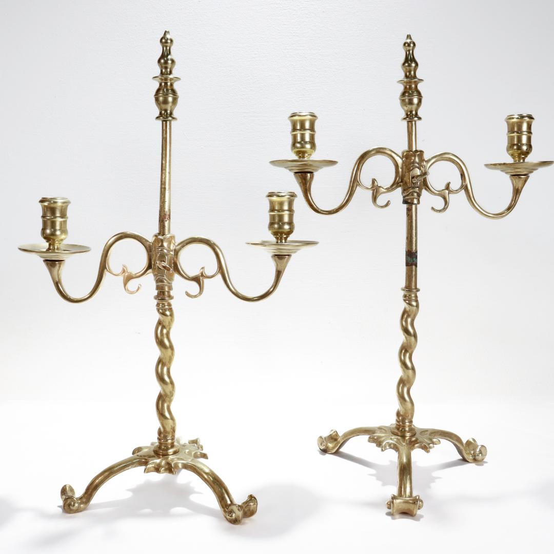 A fine pair of brass candelabra.

In the Jacobean style.

Each with tripod base and scrolled feet supporting a barley twist shaft that accommodates candelabra arms with 2 candle cups and bobeches and terminates in a turned finial.

The adjustable