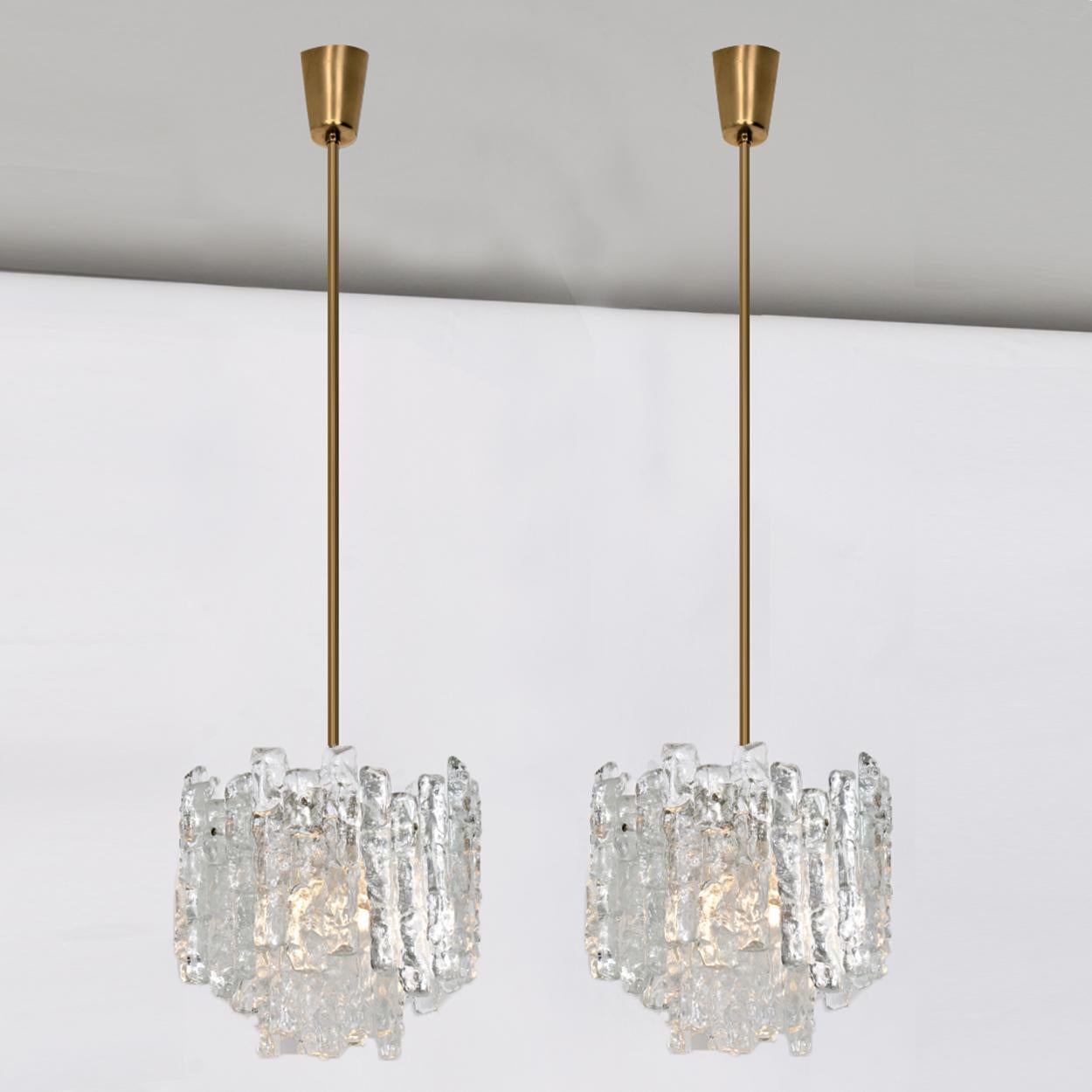 Pair of high-end and elegant modern chandeliers, manufactured by Kalmar, Austria in the 1970s. Lovely design and heavy quality. Each chandelier has six sockets and two layers of extremely stylish textured solid ice glass sheets (12 pieces) dangling