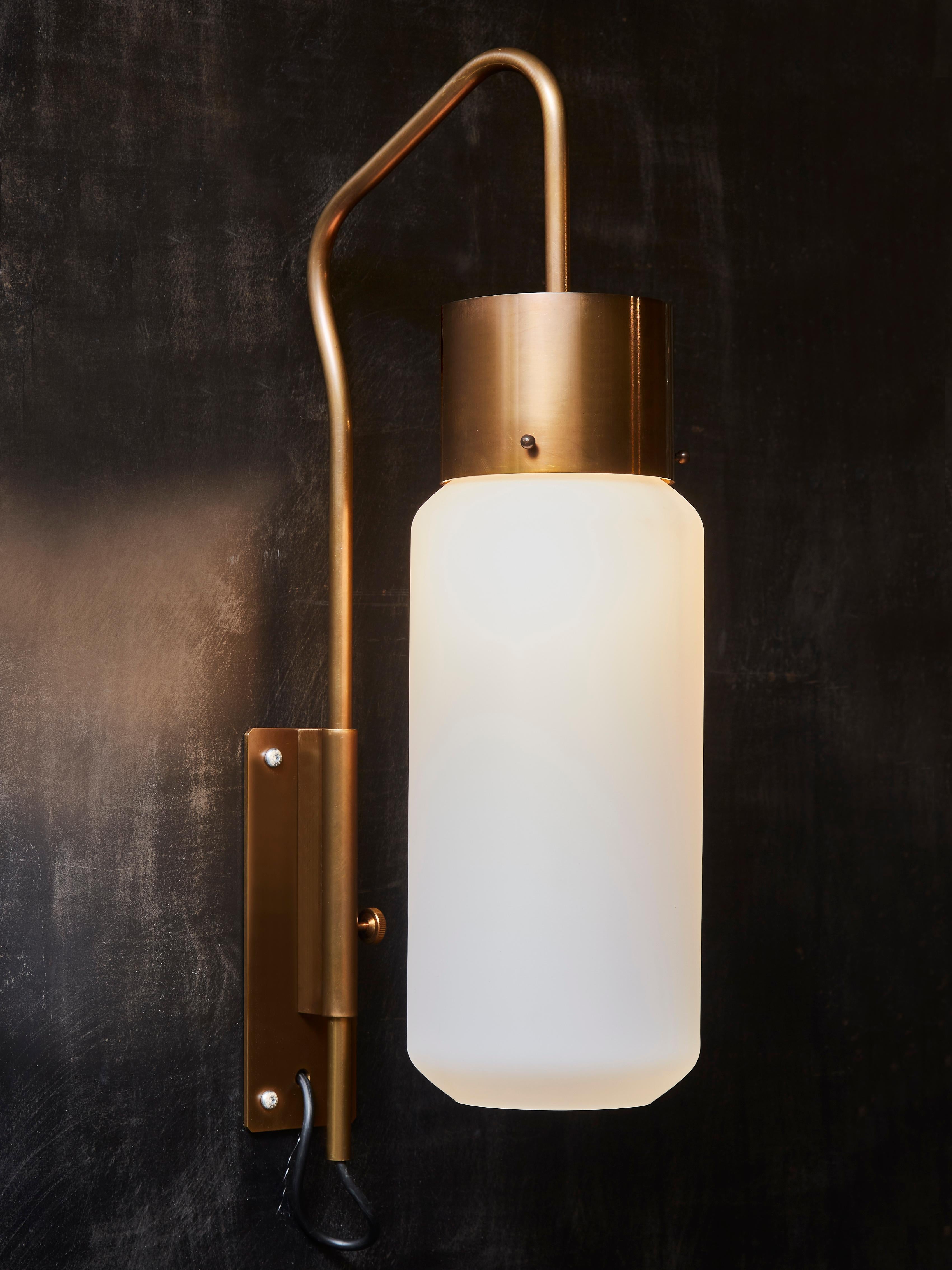 Pair of brass wall sconces with opaline glass and adjustable arm.