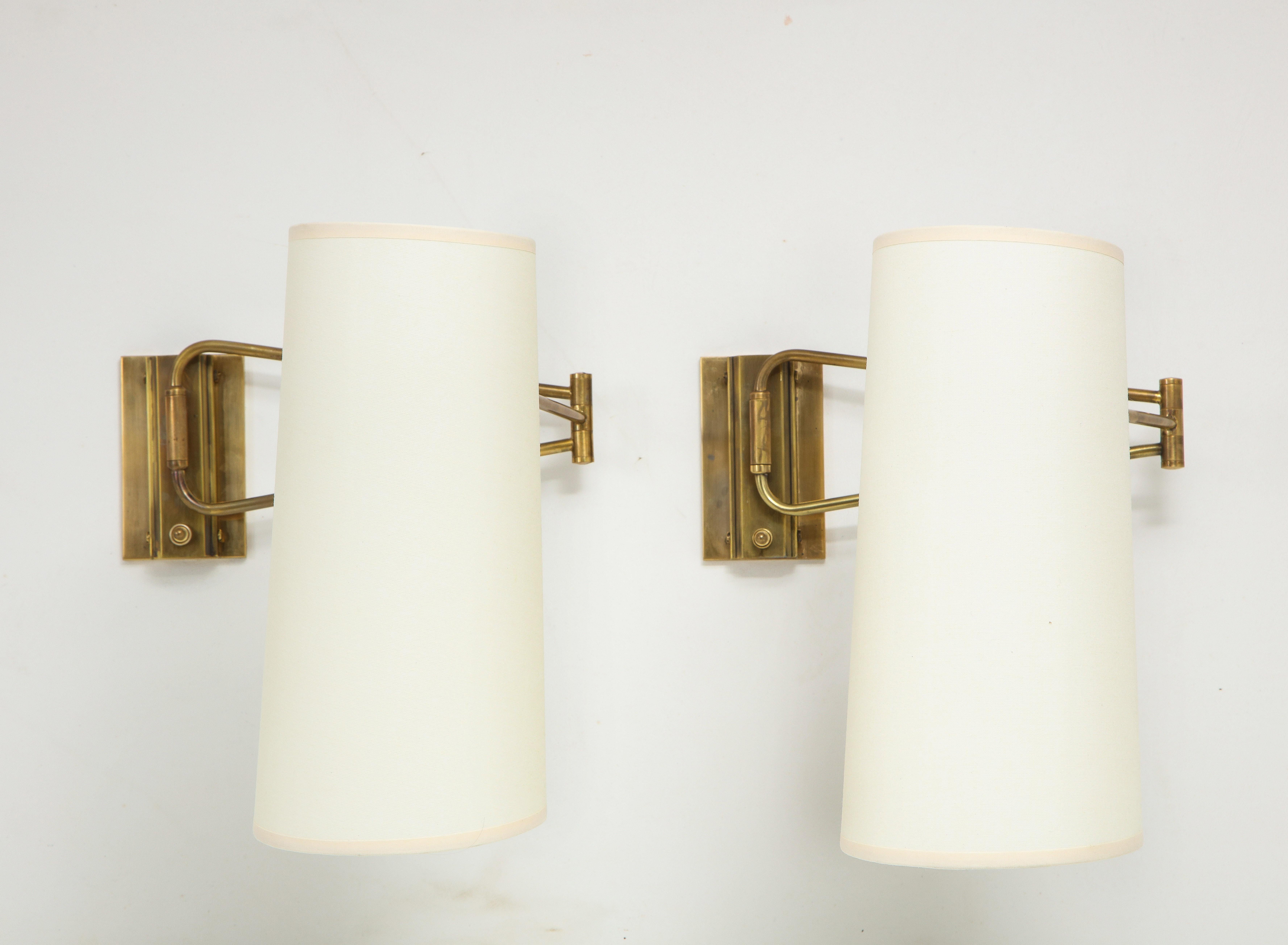 Pair of Lunel brass swingarm sconces with paper shades, newly rewired, and come with J-box backplates.