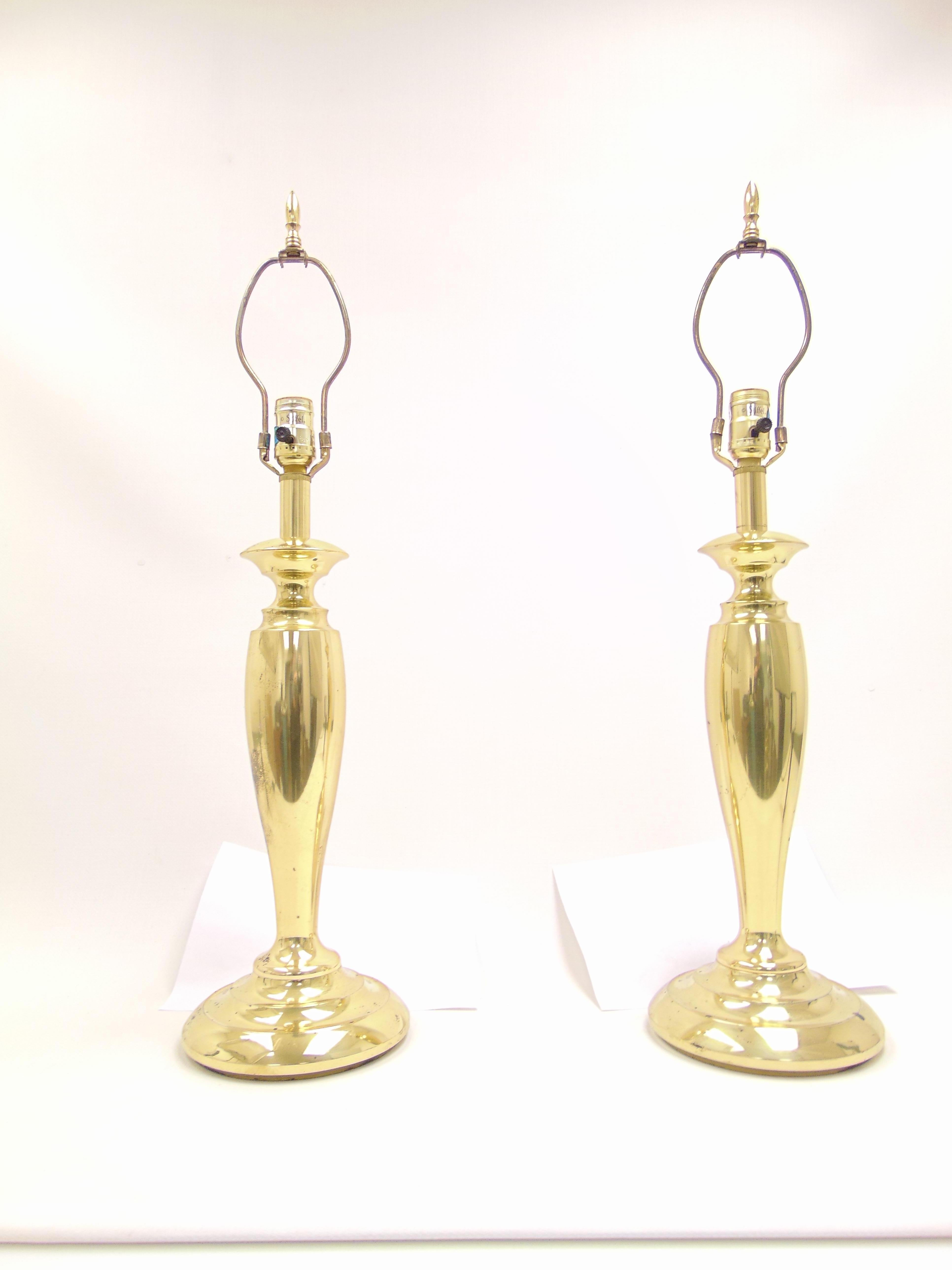 These are a beautiful classical style midcentury lamps by Stiffel with a polished brass finish. Both lamps have beautiful matching pointed finials at top. The manufacturer label is on the socket of both lamps. These are Classic polished brass lamps