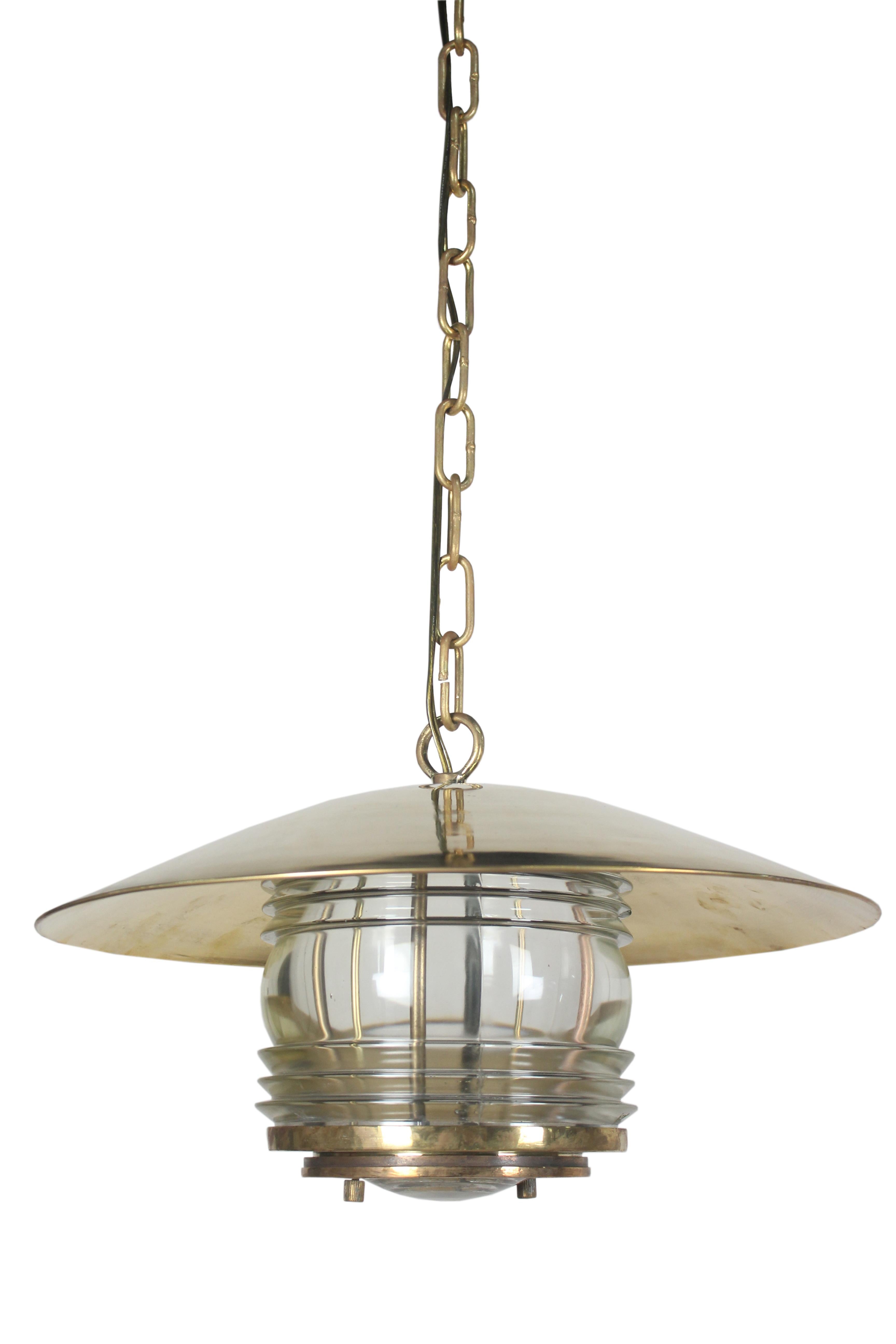A pair of brass ship's lights with Fresnel Lens glass. These were originally post lights converted to hanging pendant chandelier lights. Circa 1970's from a decommissioned ship. Originally European, rewired for American use. The plate underneath