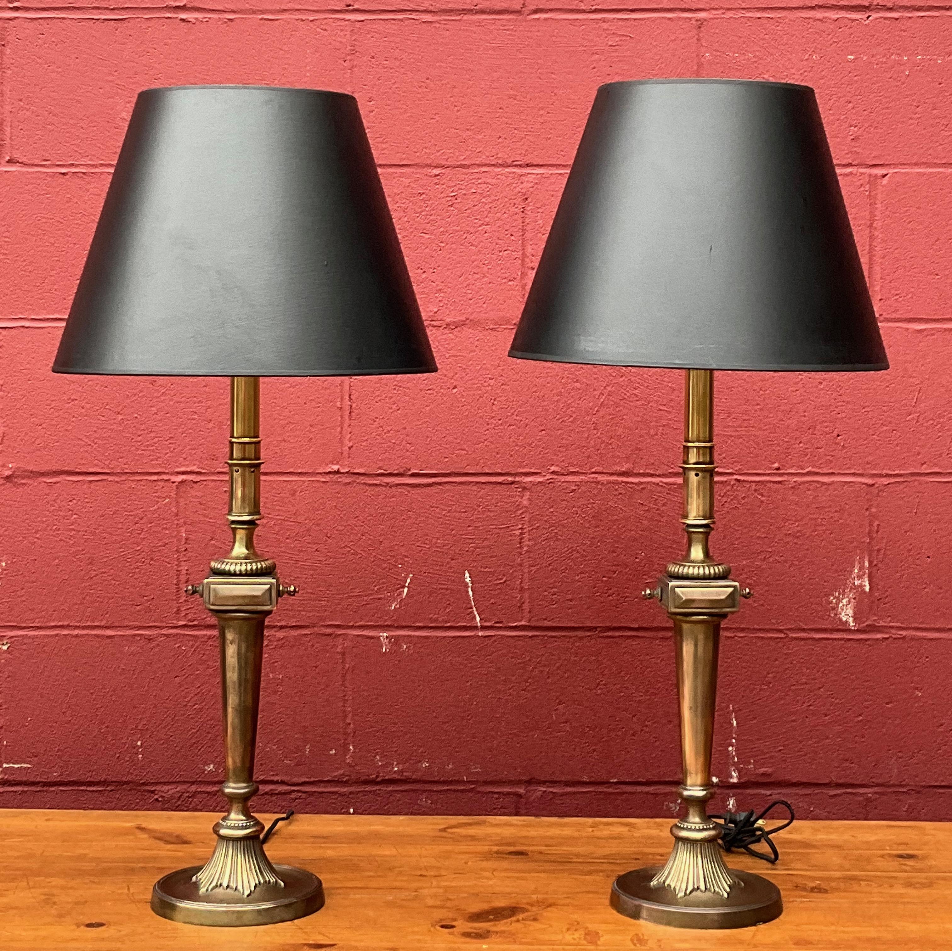 Introducing a well-made pair of American Neoclassical brass table lamps from the 1950s with an English brass finish, that have been recently rewired for optimal functionality. These lamps exhibit a charming patina, showcasing their age and