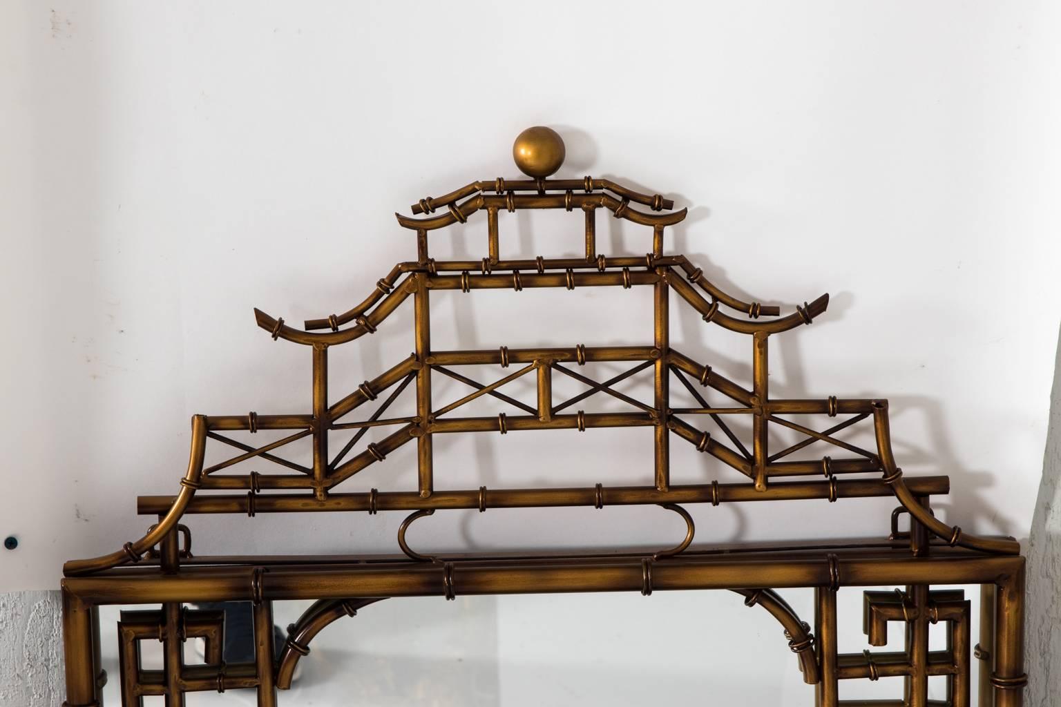 Pair of brass chinoiserie style mirrors with a pagoda roof on the crown in a faux-bamboo finish, circa 20th century.
 