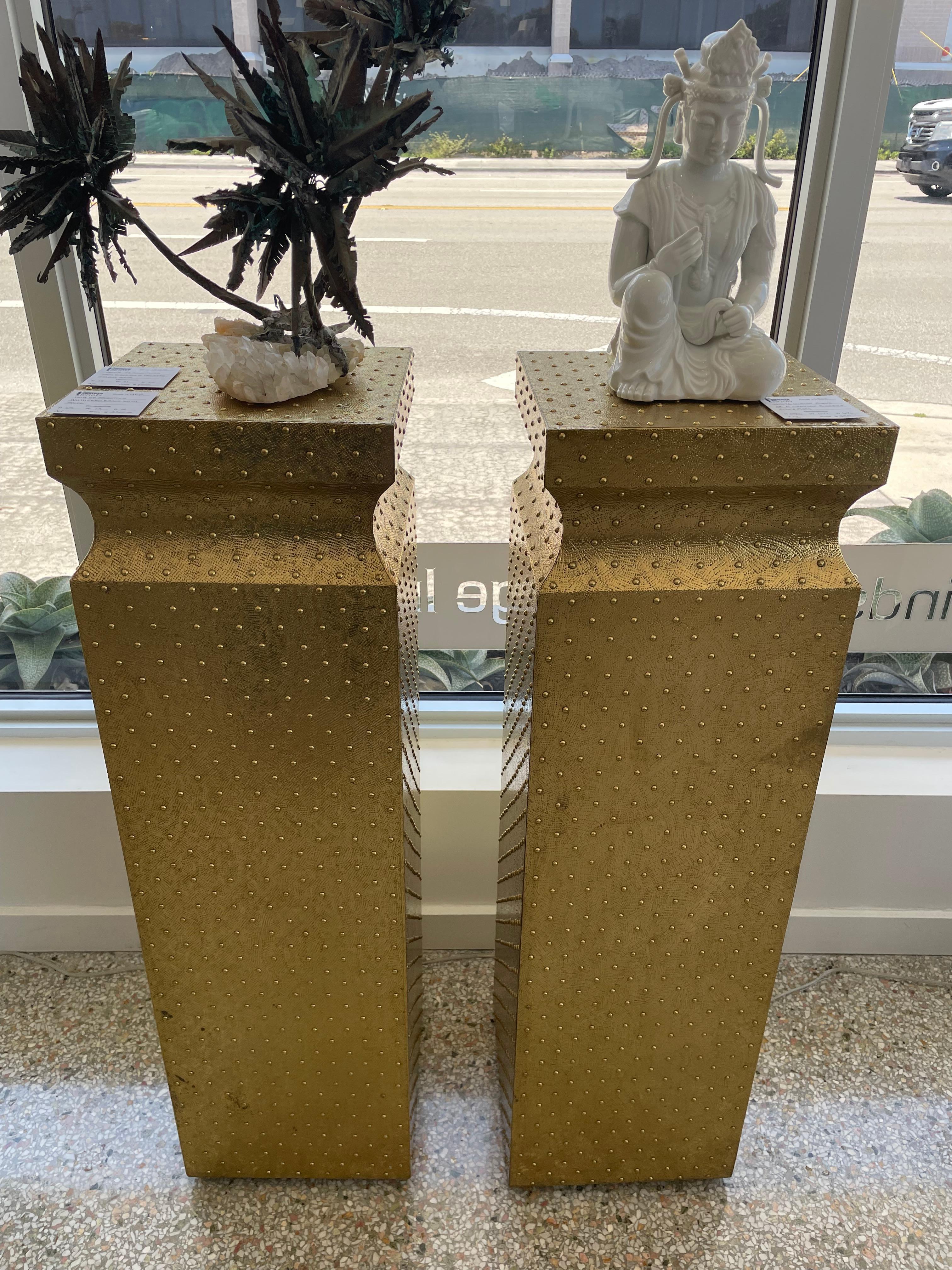 This stylish and chic pair of brass clad pedestals date to the latter part of the 20th century and were acquired from a Miami Beach estate.  The piece are fabricated with sheets of brass, tooled and detailed with brass studs.

Note: There is dark