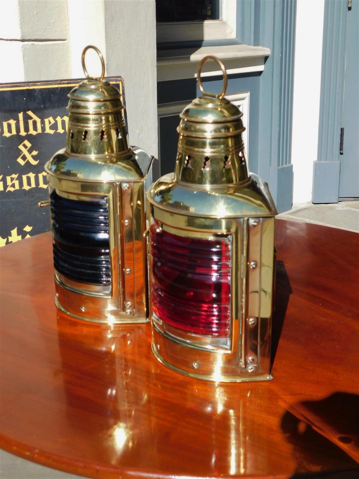 Pair of American brass port and starboard ship lanterns with flanking ringed vented domes, hinged doors, rear mounting brackets, and original colored red & blue Fresnel lenses. Lanterns retain the original interior fonts and can be electrified if