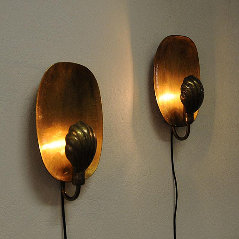 Pair of really beautiful hand-hammered brass Wall Sconces with shell shaped lampshades by Designer Lars Holmstro¨m, Arvika - Sweden. Produced in the 1950s. The brass shades has a nice shape of a shell and delivers a warm light and shine. Original