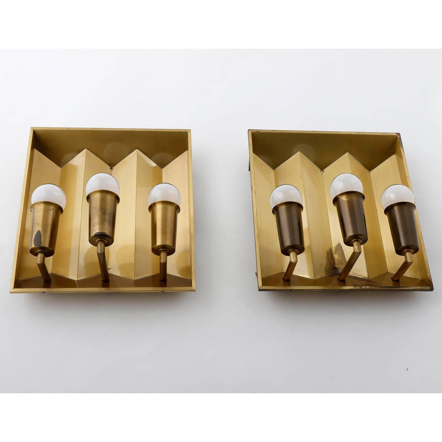 A pair of brass wall lamps by Fog & Morup in the style of Hans-Agne Jakobsson, manufactured in midcentury, circa 1960 (late 1950s or early 1960s).
Each lamp takes three E14 candelabra screw base bulbs with max. 40Watt per bulb.  They work well with