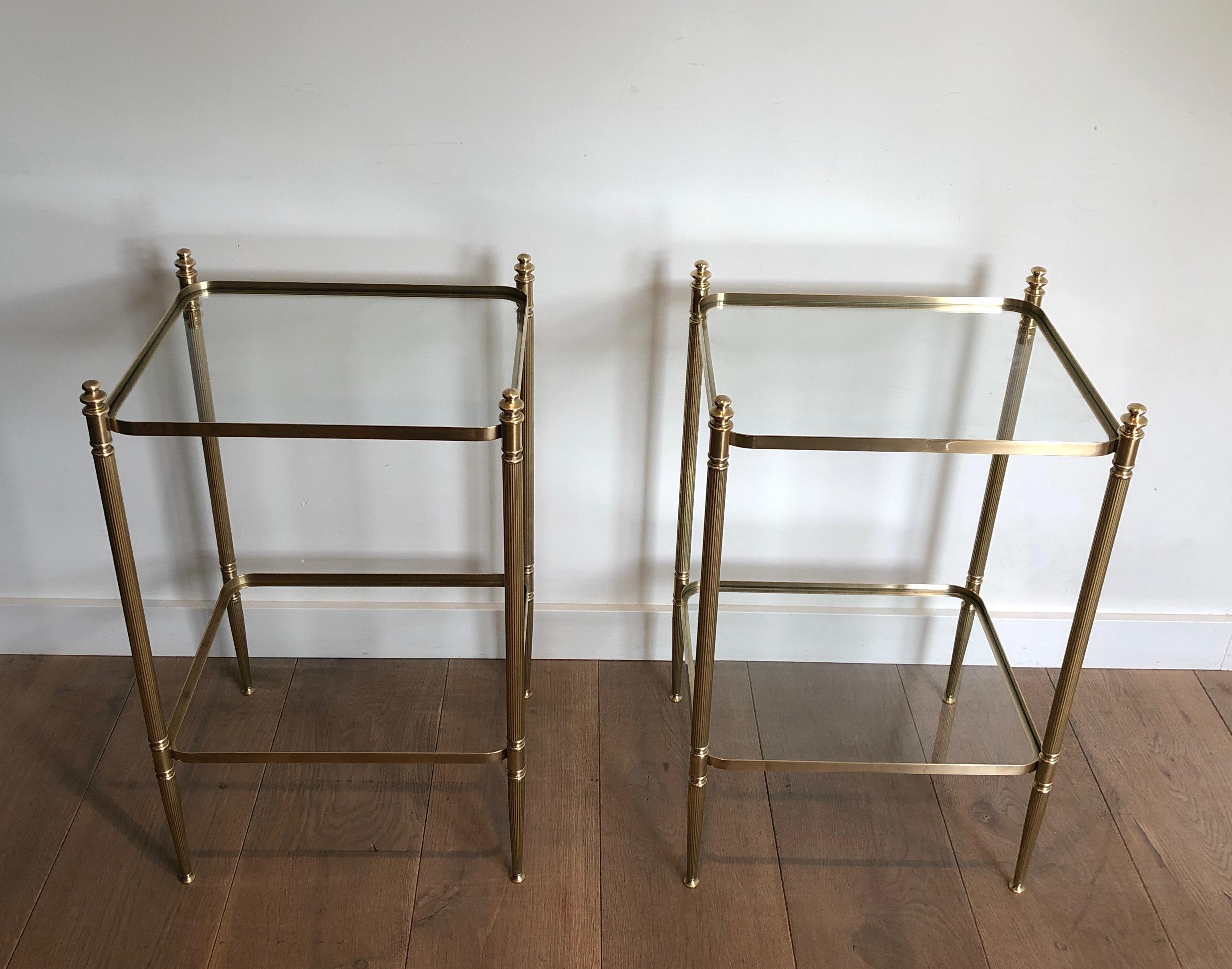 This very nice pair of neoclassical style side tables is made of brass with glass shelves. The tables are very elegant, rounded on the corners with fluted legs and nice finials. Both tables are in very good condition and have been perfectly