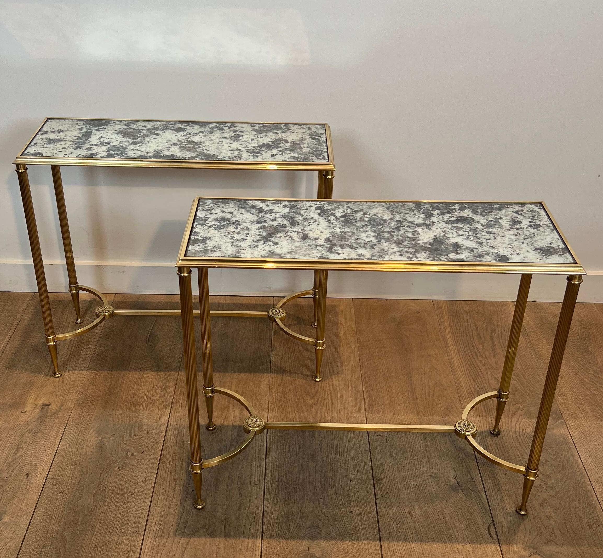 This beautiful pair of neoclassical style side tables is made of brass with oxidized mirror tops. On the bottom, the stretcher is very nice and finely chiseled. This is a French work by Maison Baguès. Circa 1940