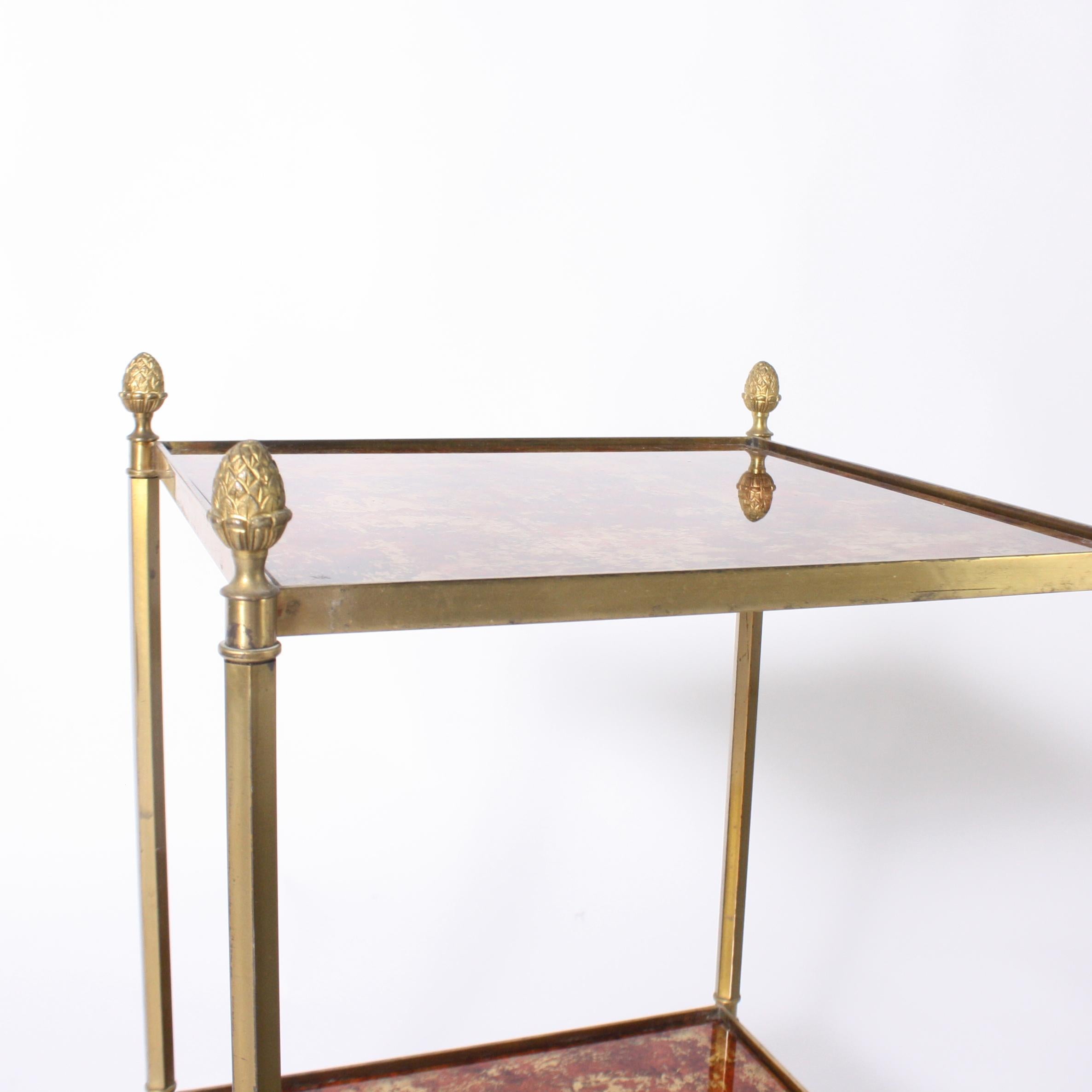 Pair of brass side tables with reverse painted glass shelves, circa 1950.
 