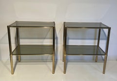 Pair of brass side tables with smoked glass shelves. French Work. Circa 1970