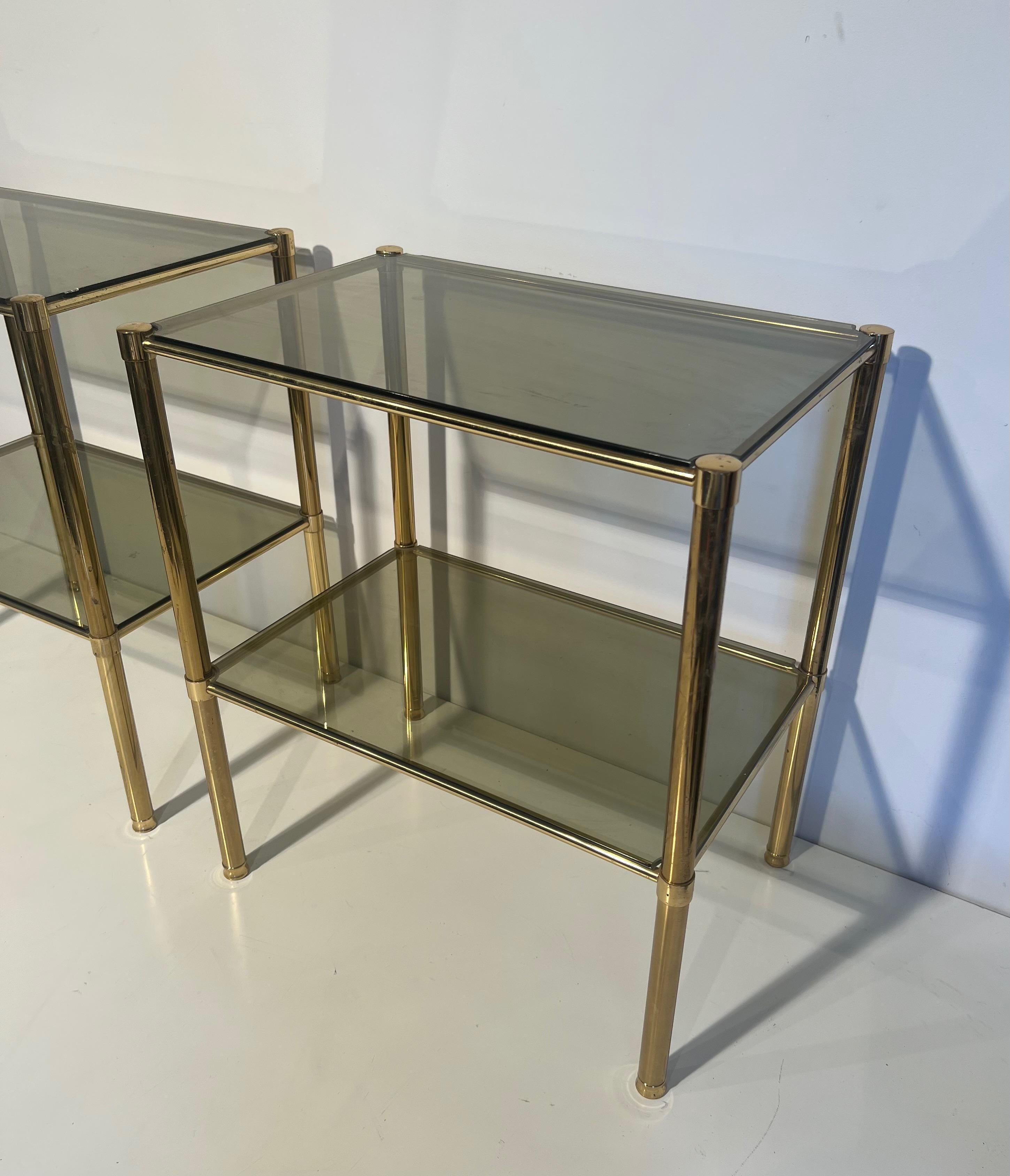 Mid-Century Modern Paire de tables d'appoint en laiton avec étagères en verre fumé. Travail en français. Circa 1970 en vente