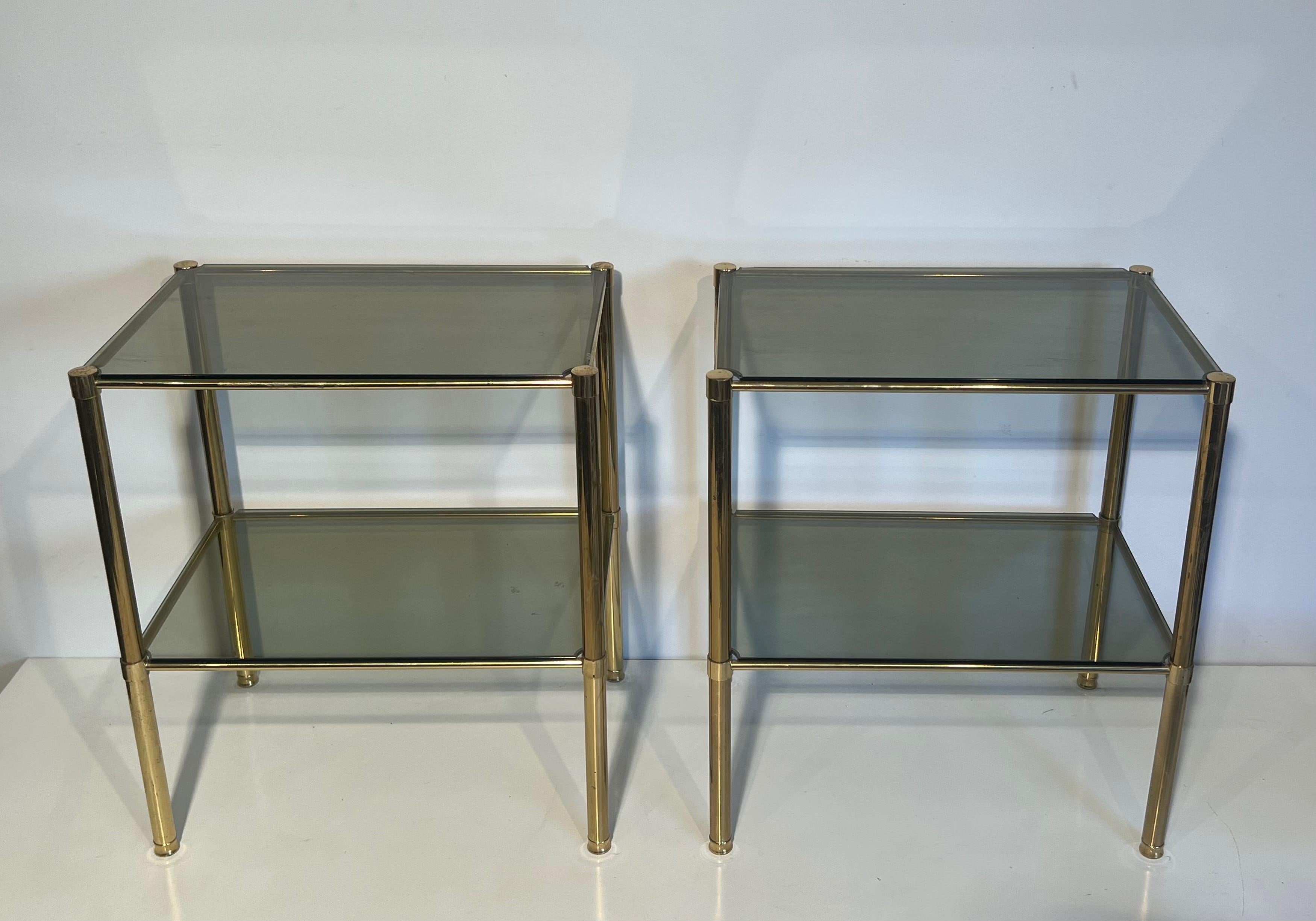 Laiton Paire de tables d'appoint en laiton avec étagères en verre fumé. Travail en français. Circa 1970 en vente