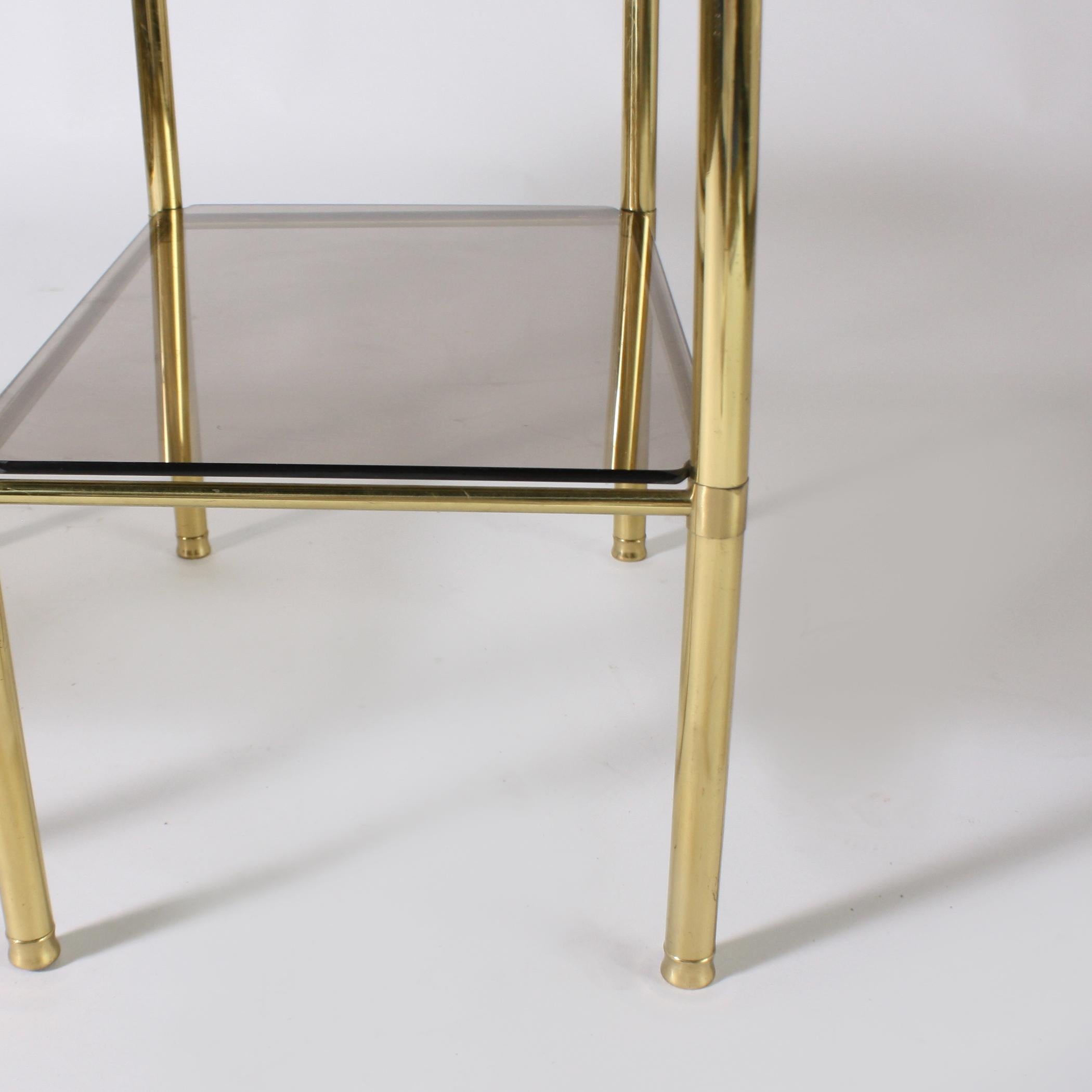 Pair of brass side tables with smoky glass tops, circa 1950.
  