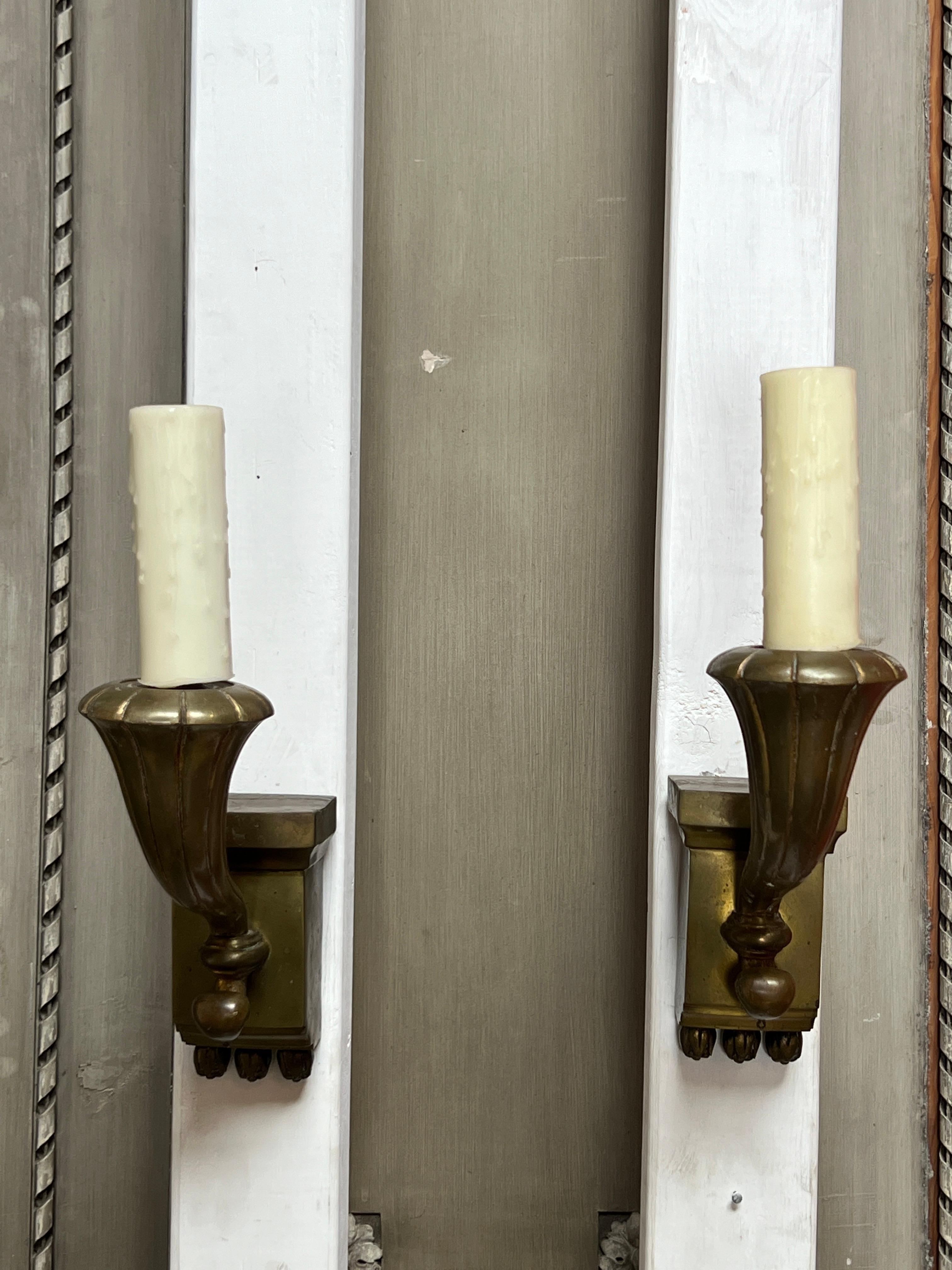 A pair of French Bronze single arm sconces, wall lights in a neoclassical style or Hollywood regency.  The arms are are a stylized cornucopias.  
These large scaled sconces are very decorative and bold.  