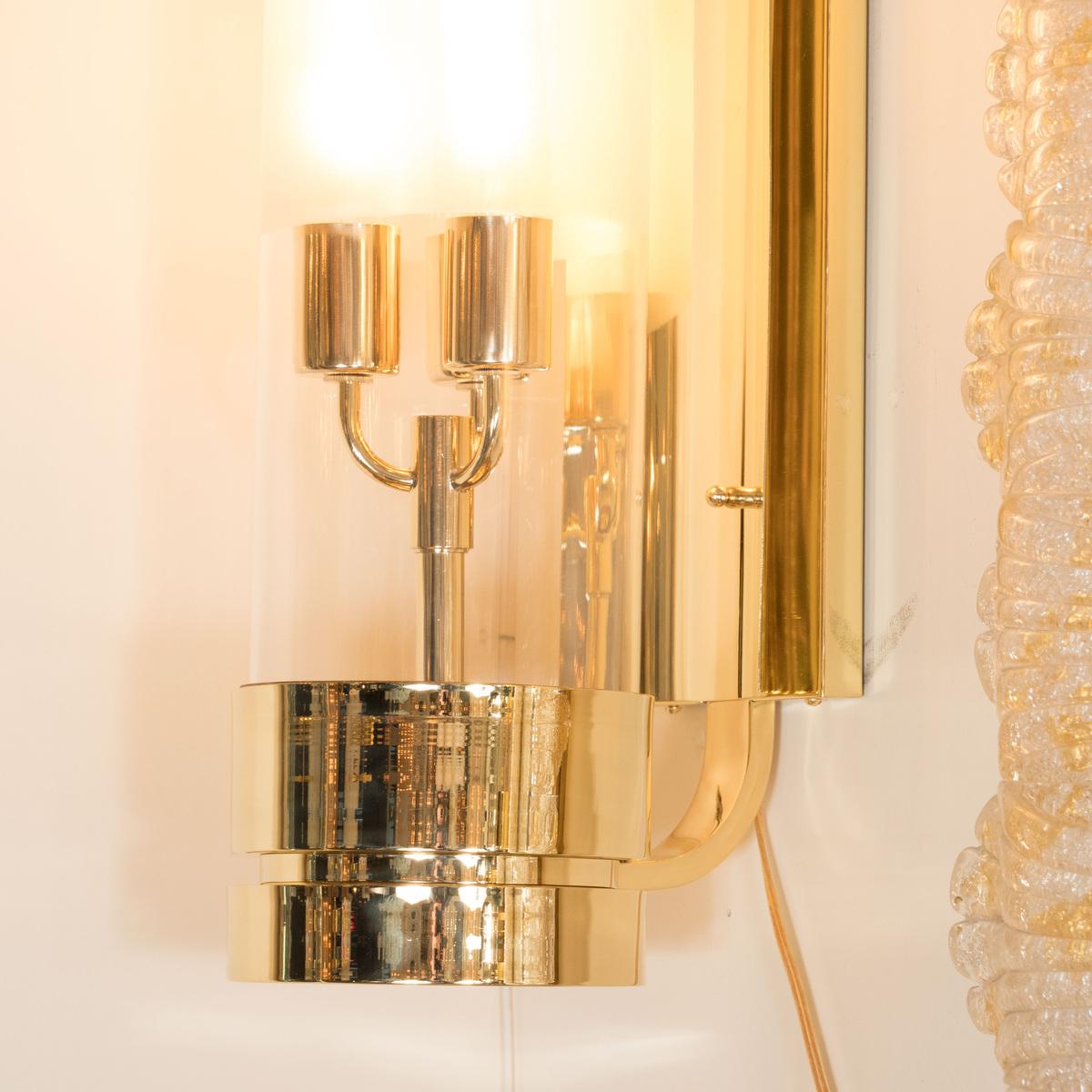 Pair of brass single arm sconces with cylindrical Lucite shades.