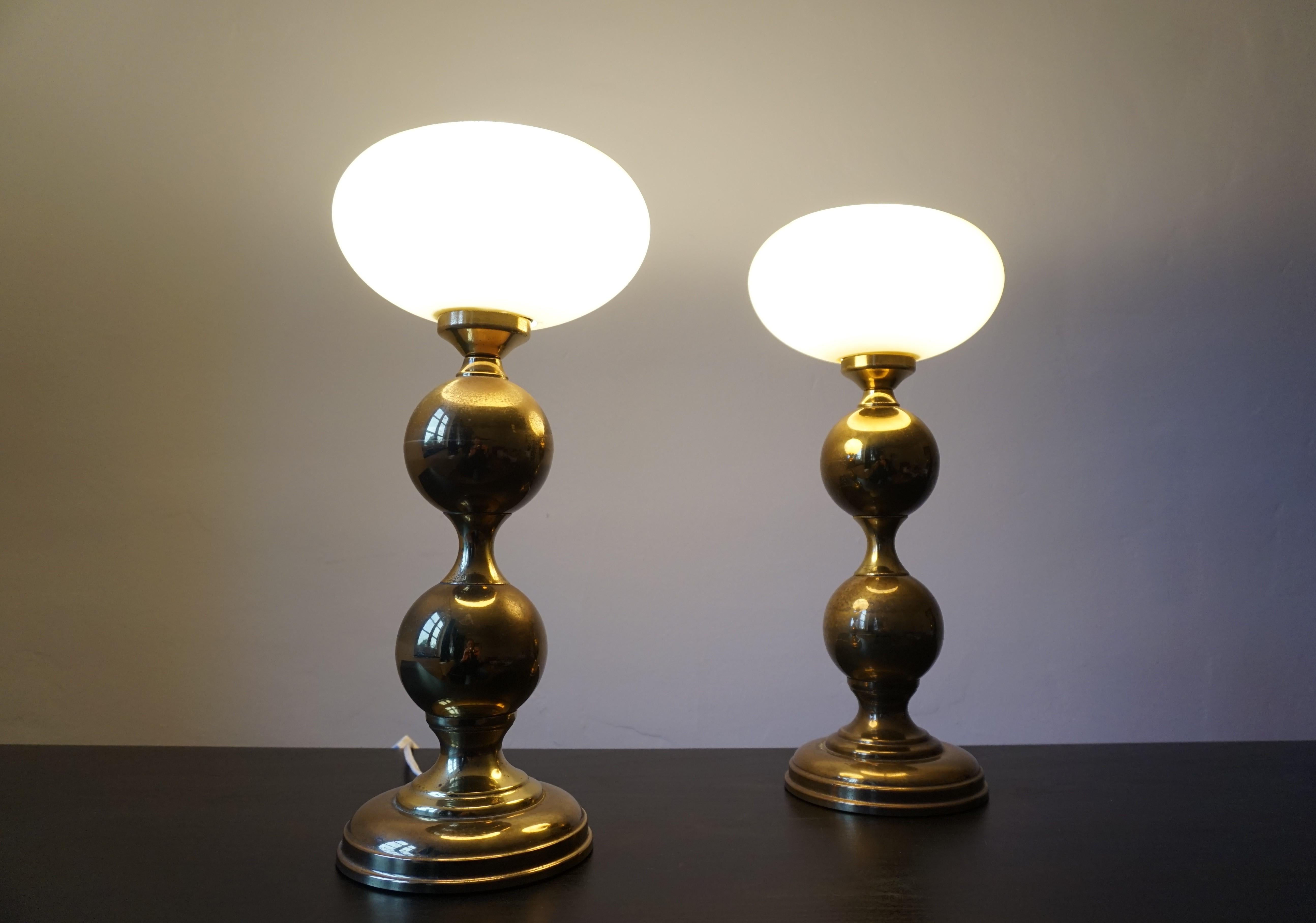 A set of 2 brass lamps with an attractive patina from the 70s. The lamps have a lamp base made of 2 spherical shapes and a glass bowl made of beige glass as a lampshade. The brass of the lamp bases has acquired a certain patina over time. The glass
