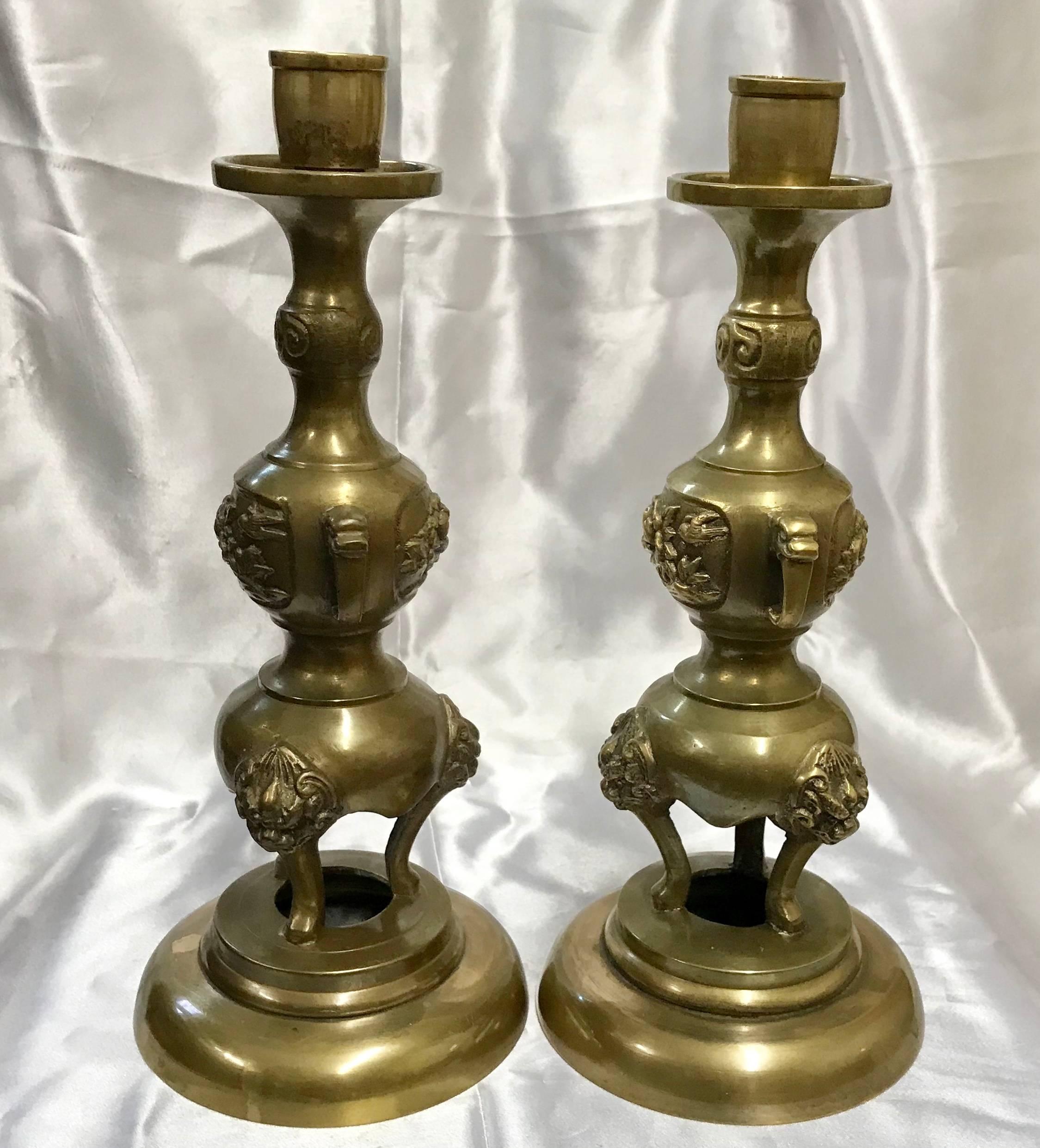 We are offering a pair of heavy cast brass candlesticks with several personalities. Starting at the smooth base, you will find three legs with each supporting the head of a griffin. Further up, you will find dainty flowers bordered by handles with