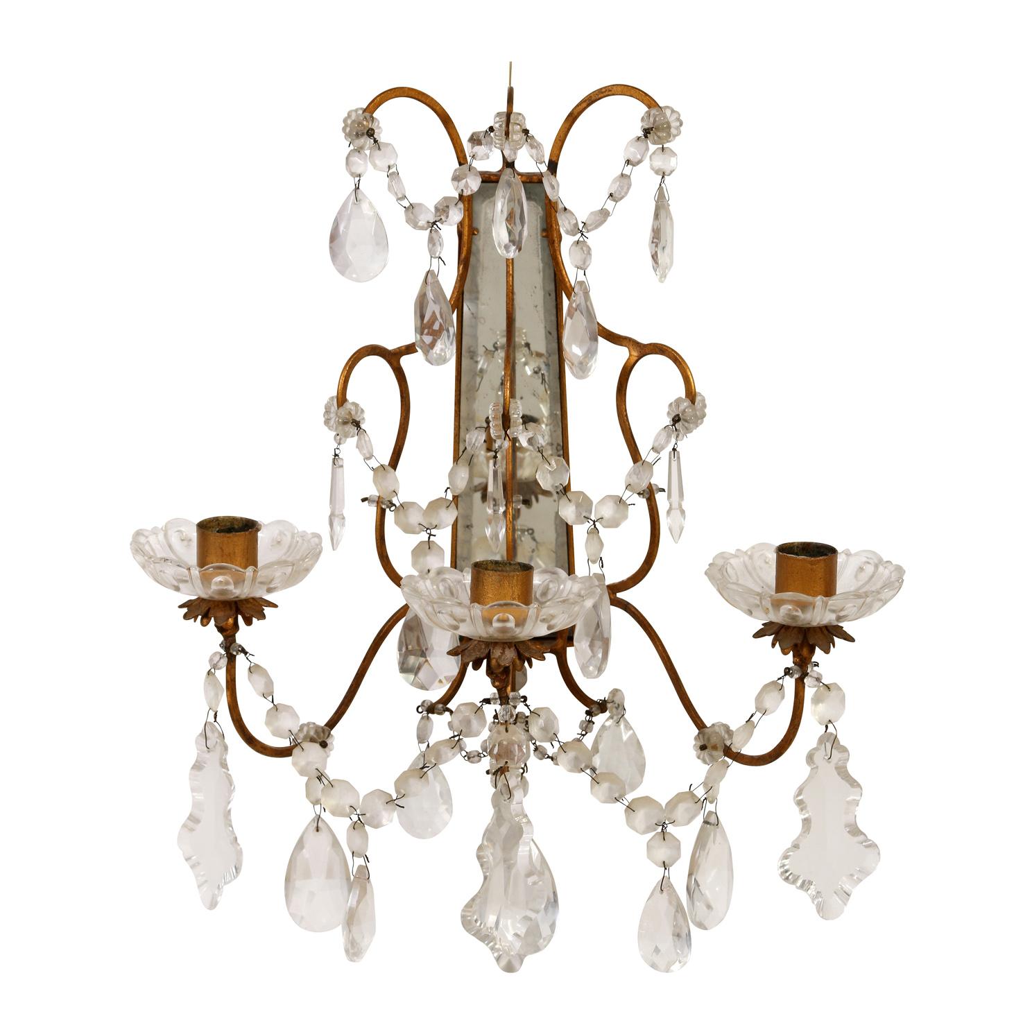 A vintage pair of brass three arm candle sconces with crystal bobeches, swags and drops, and mirror backs.