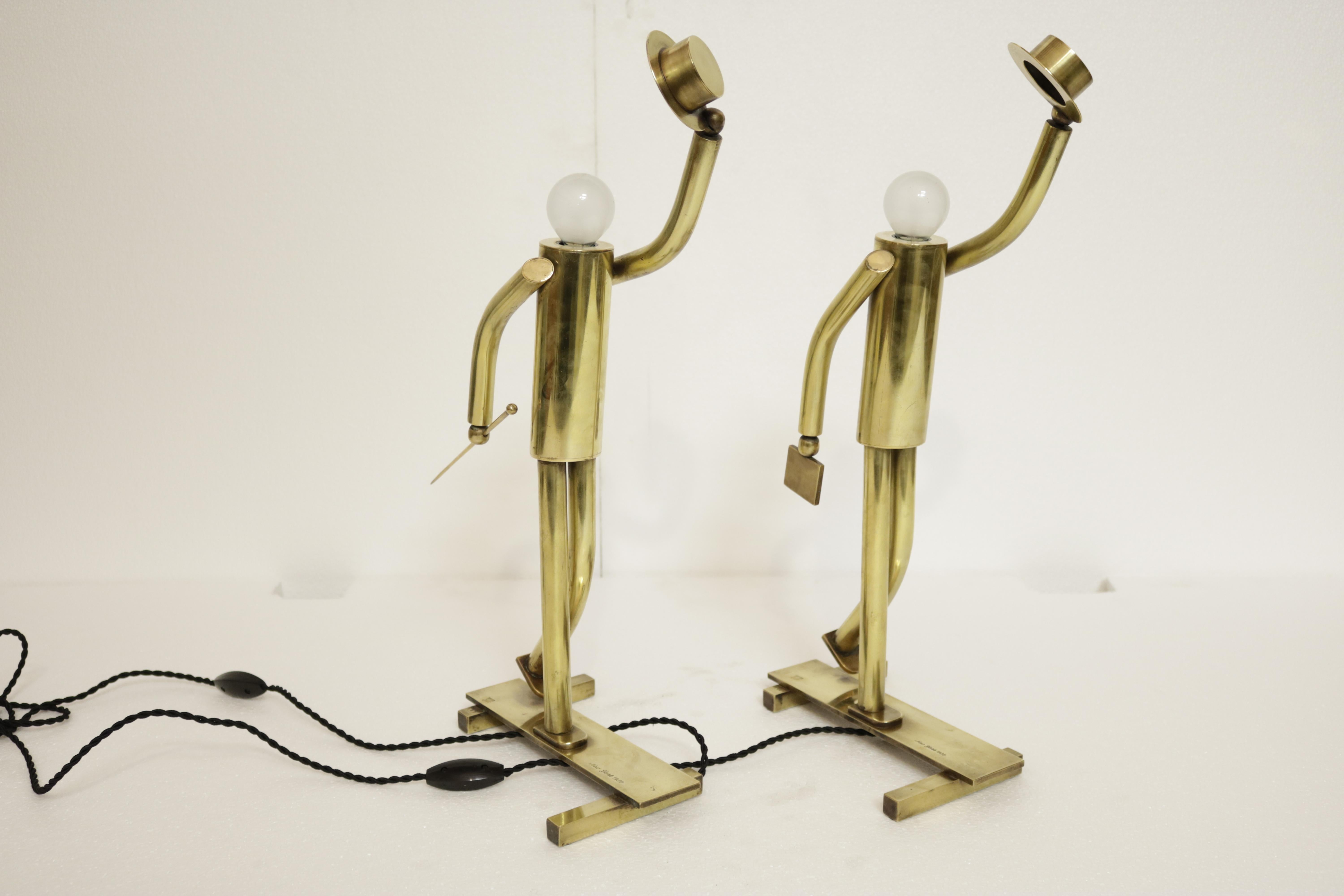 Unique pair of high-end brass lamps in the form of sphere bulb-headed figurines sporting top hats and cane or suitcase. The words 