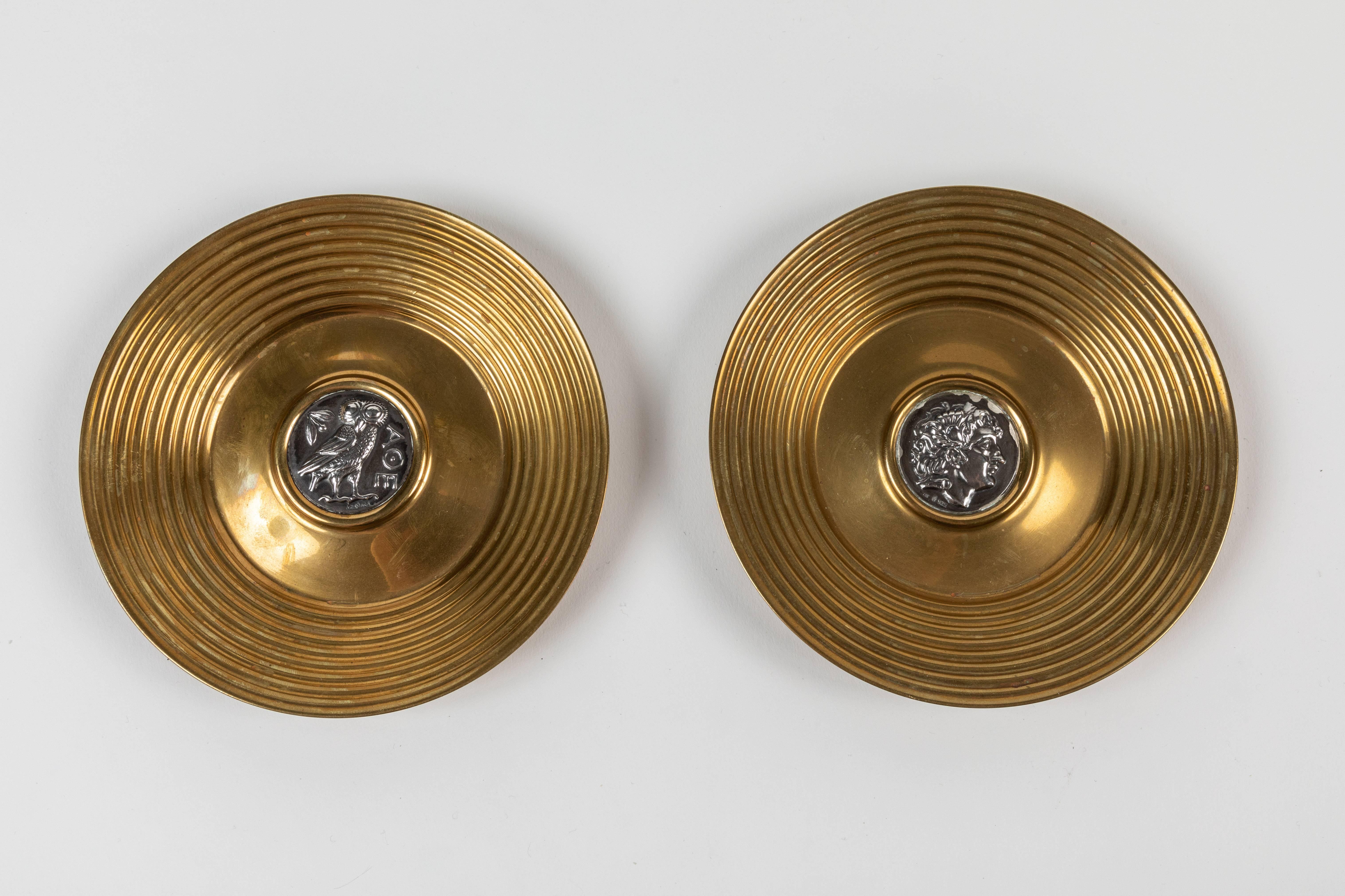 Ein Paar Schmuckschalen aus Messing und Sterlingsilber von Ilias Lalaounis, Griechenland. In der Mitte jedes Tellers ist eine griechische Sterlingsilbermünze (Replik) eingelassen. Auf der einen Münze ist die 