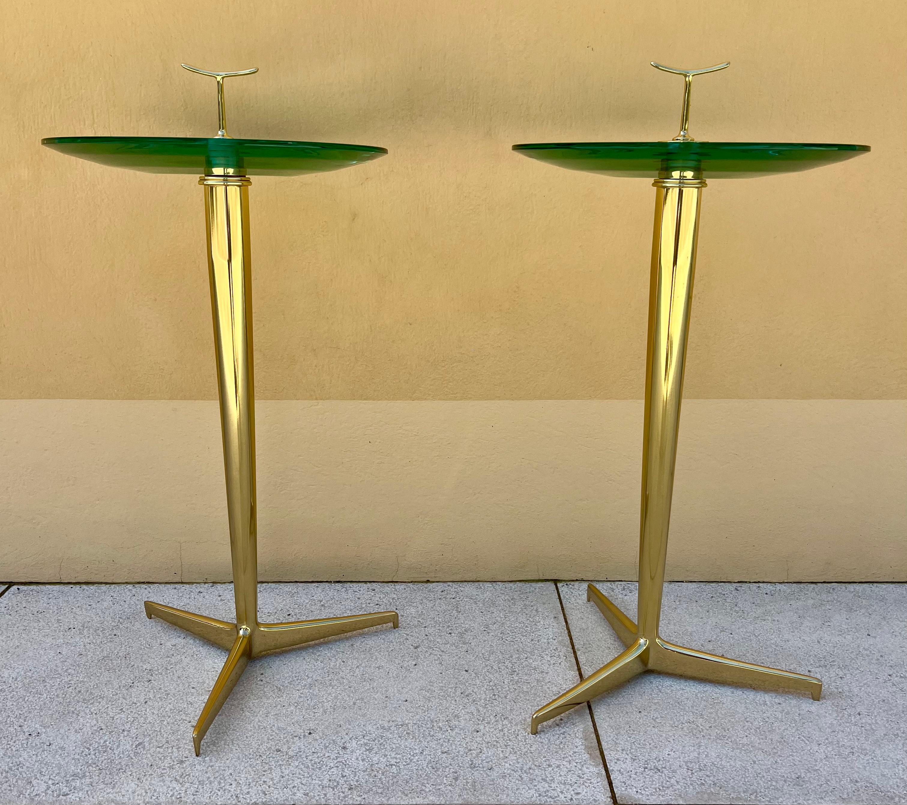 Elegant pair of side tables 
Brass tripod foot,
Brass handle;
Thick glass tray, the bottom curved and cut to produce a lens effect. 
Italy, circa 1980
The design of this gueridon is attributed to Angelo Ostuni or to Giuseppe Ostuni

Dimensions: