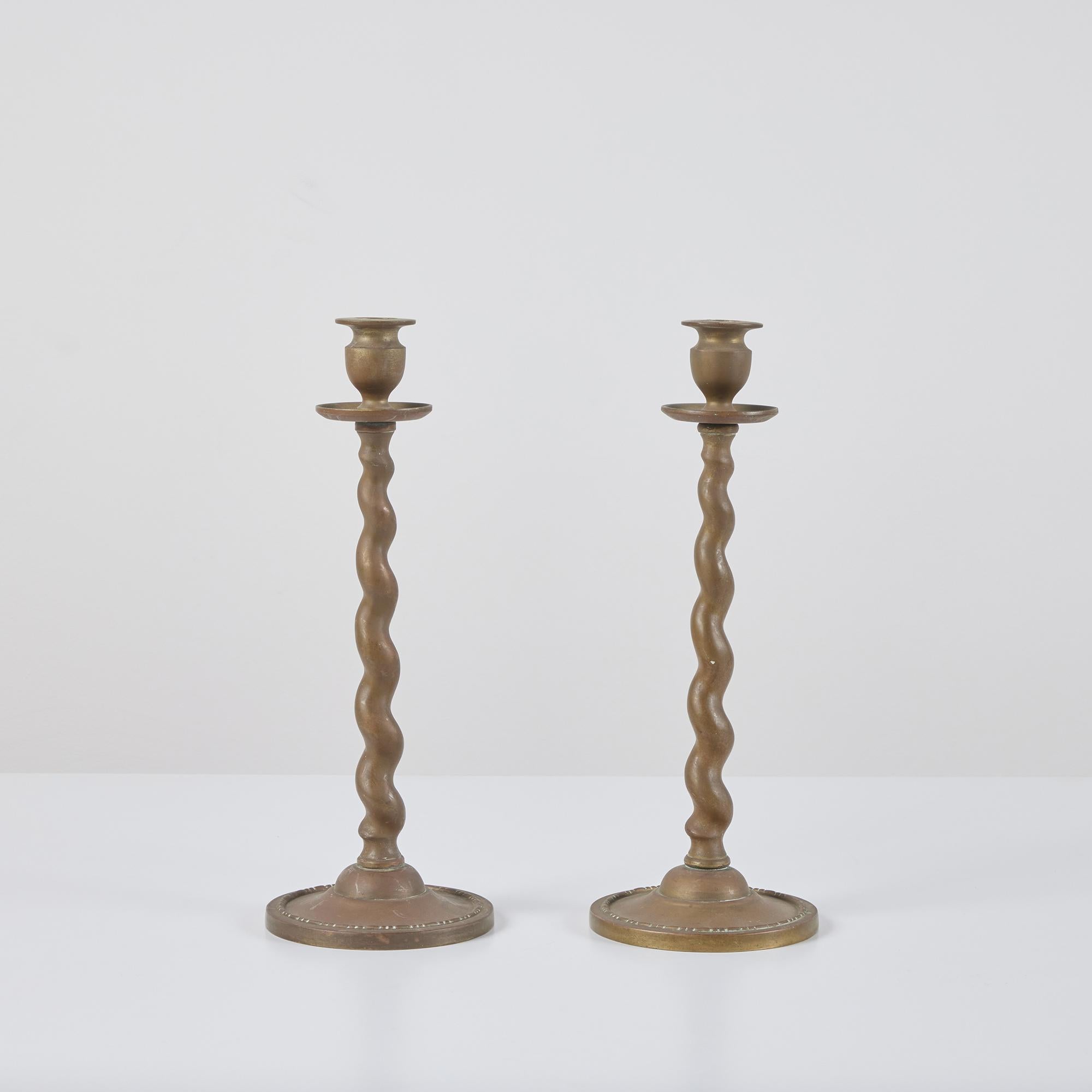 Pair of solid brass candlesticks, in the style of Peerage, England. The pair of beautifully patinated candlesticks feature barley twist stems and round tiered bases.

Dimensions
5.25