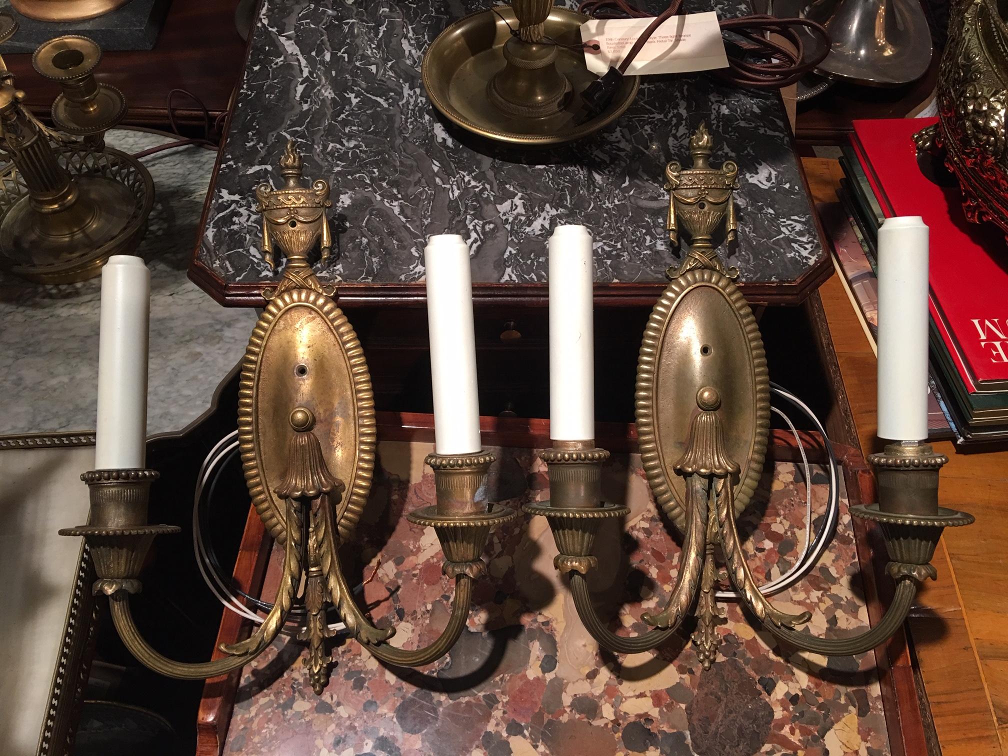 Pair of brass two-light oval back with urn top sconces, late 19th century.