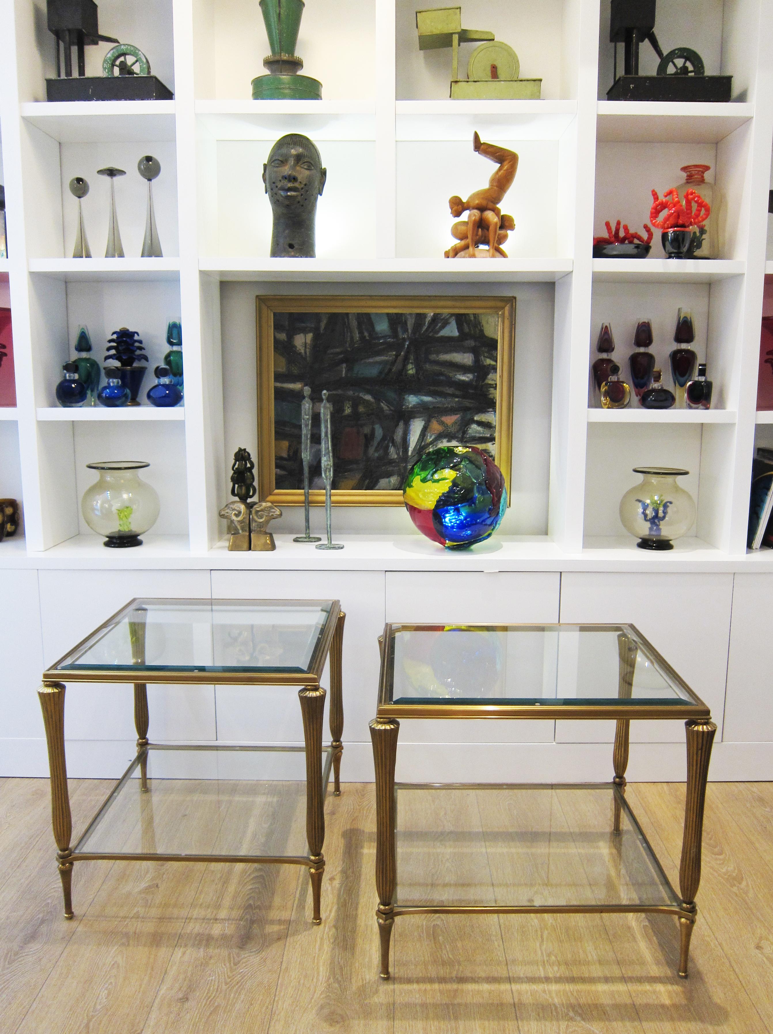 Two tier brass side tables with beveled glass inset tops and bottoms.
