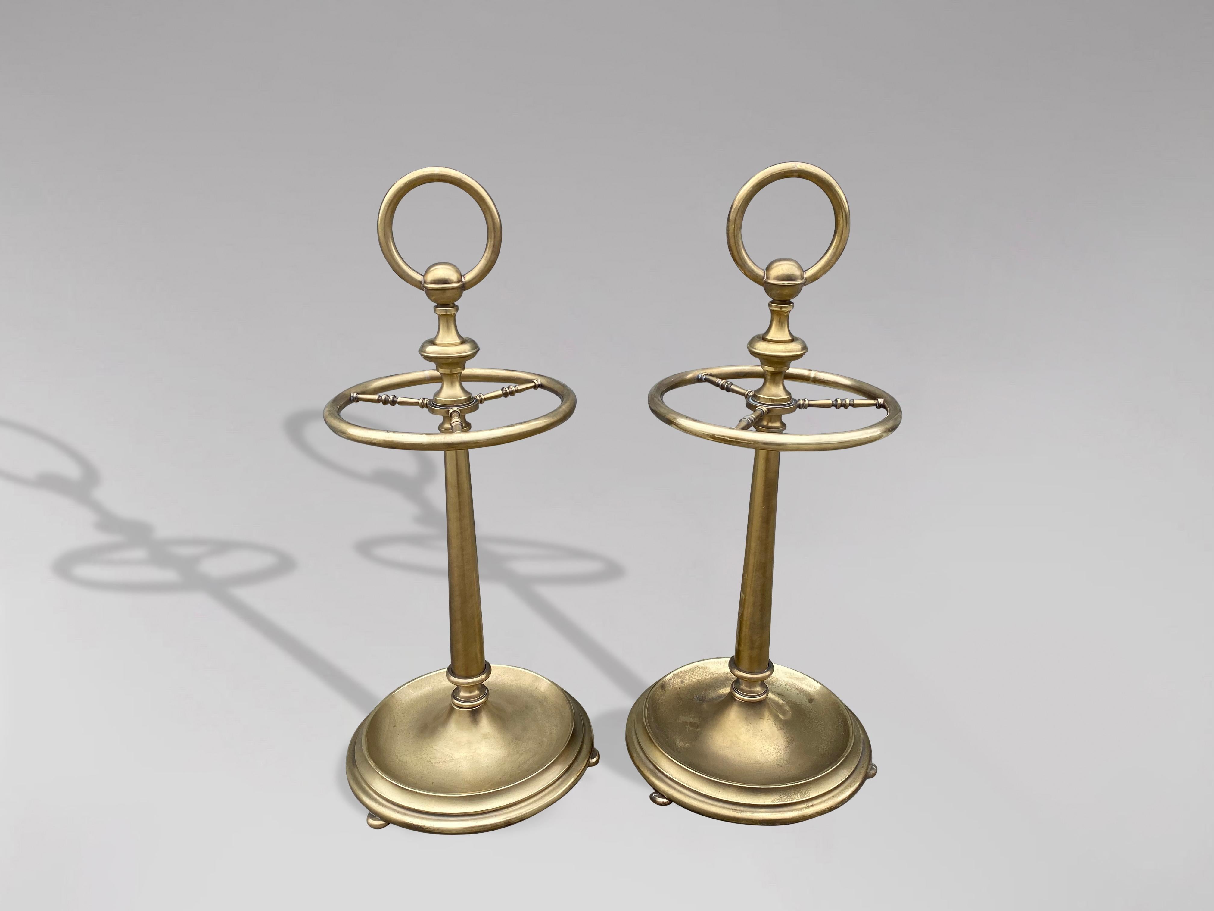 A pair of 20th century brass umbrella stands or stick stands. Polished brass large circular handle above a top divided into four sections to hold either walking sticks or umbrellas. Circular umbrella brass valet rack with four sections and large