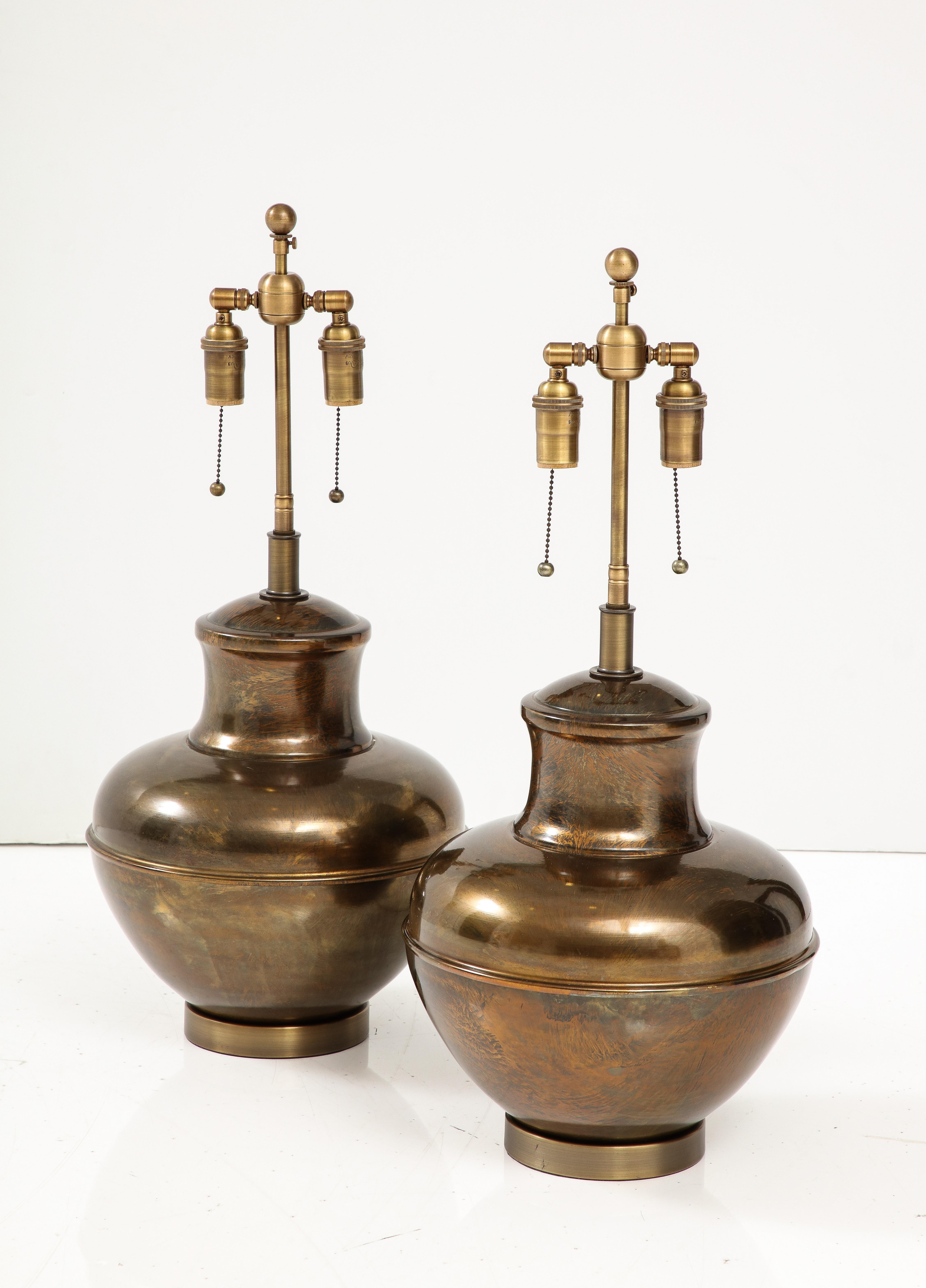 Pair of Mid-Century Brass Urn shaped lamps.
The lamps have been Newly rewired with adjustable Antique Brass finished 
double clusters that take standard size light bulbs and silk rayon cords.
Each socket can take up to  60 Watts / 120 Watts maximum