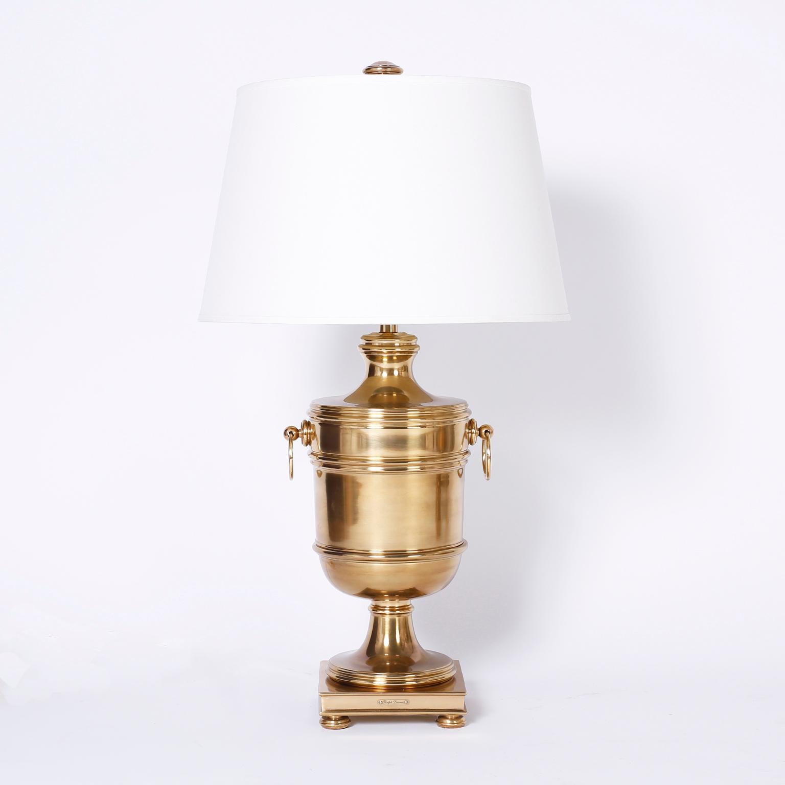 Handsome pair of brass table lamps with a Classic urn form, side ring handles, square plinth, and turned feet and finials. Hand polished and lacquered for easy care. Signed Ralph Lauren on a brass plaque.