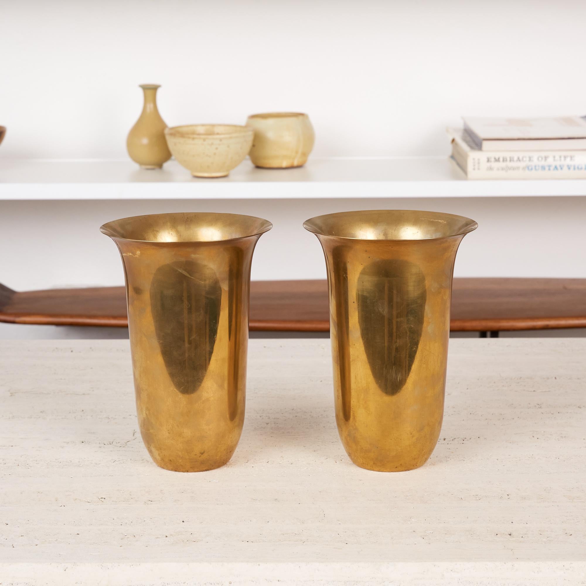Pair of rare brass vases by Walter Von Nessen for Chase, USA, circa 1930s. The pair of solid patinated brass Art Deco vases are impressed with [Chase] and feature the Chase Minotaur Archer logo on the underside. The Chase Brass and Copper Company of