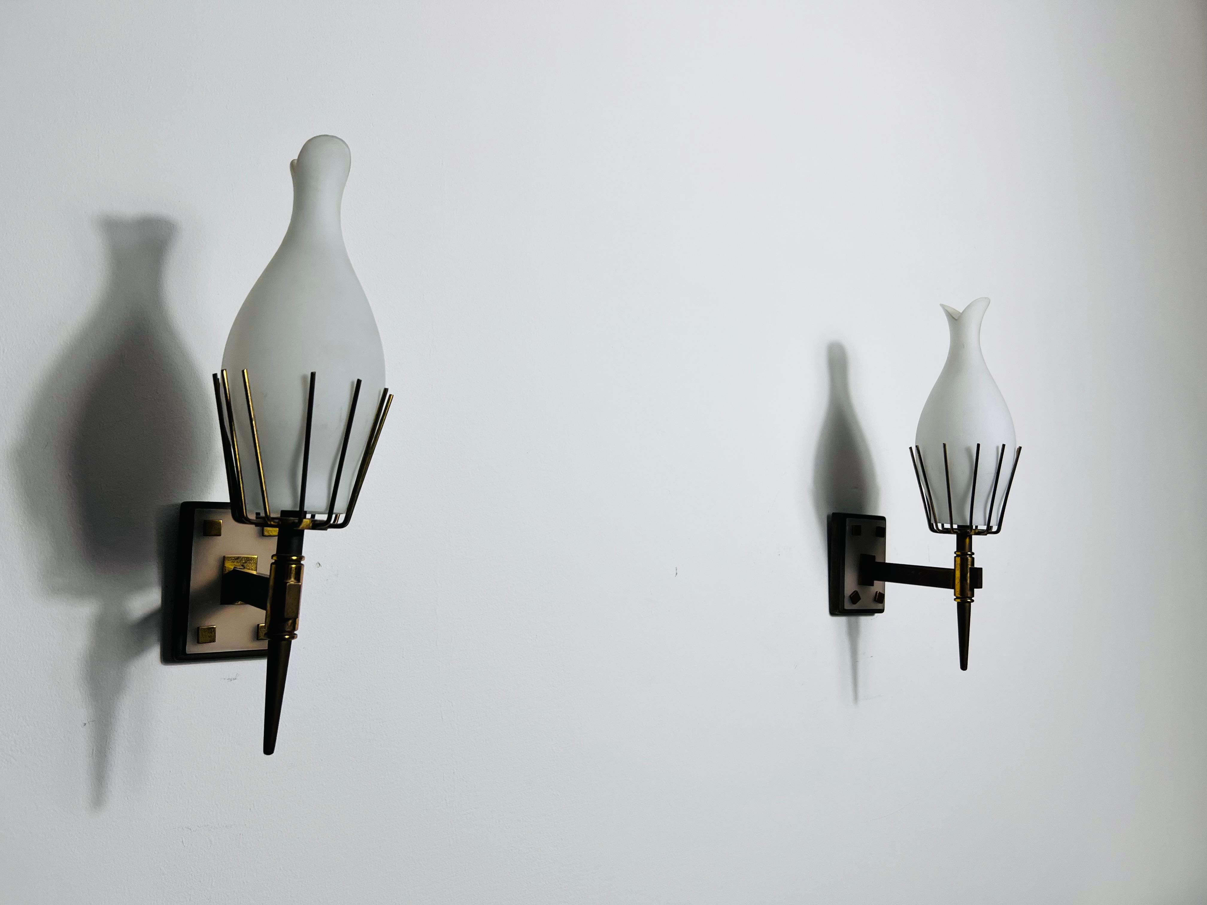 Cette paire d'appliques exquises, datant de l'Italie des années 1960, incarne l'élégance et le savoir-faire du design moderne du milieu du siècle. Attribuées au célèbre fabricant italien Arredoluce, ces lampes sont des classiques intemporels pour