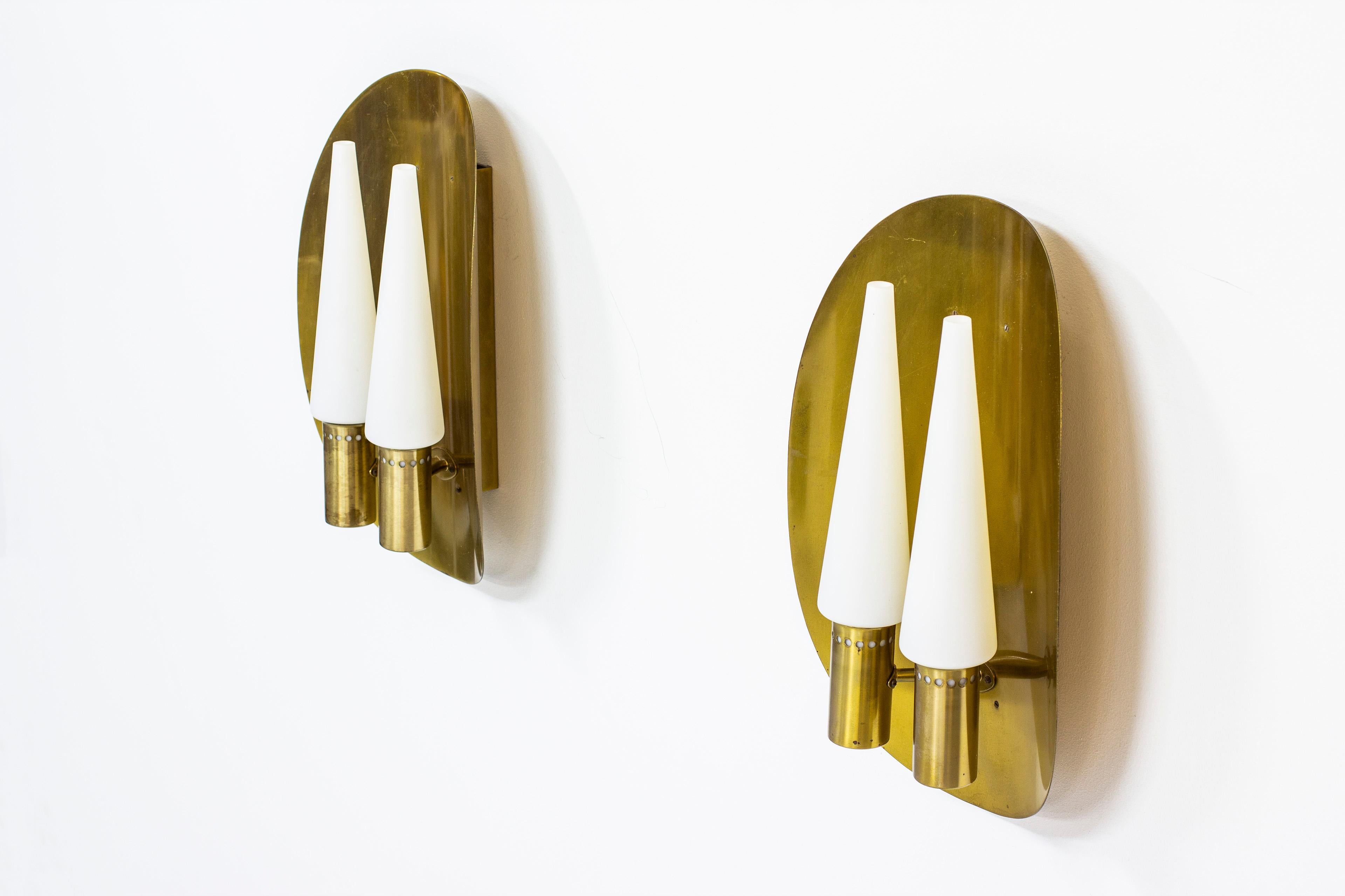 Ein Paar Wandlampen von Hans-Agne Jakobsson. Produziert von Hans-Agne Jakobsson AB in Schweden in den 1960er bis 1970er Jahren. Hergestellt aus massivem Messing mit vier konischen Opalglasschirmen. Beide Lampen signiert mit Etikett. Sehr guter