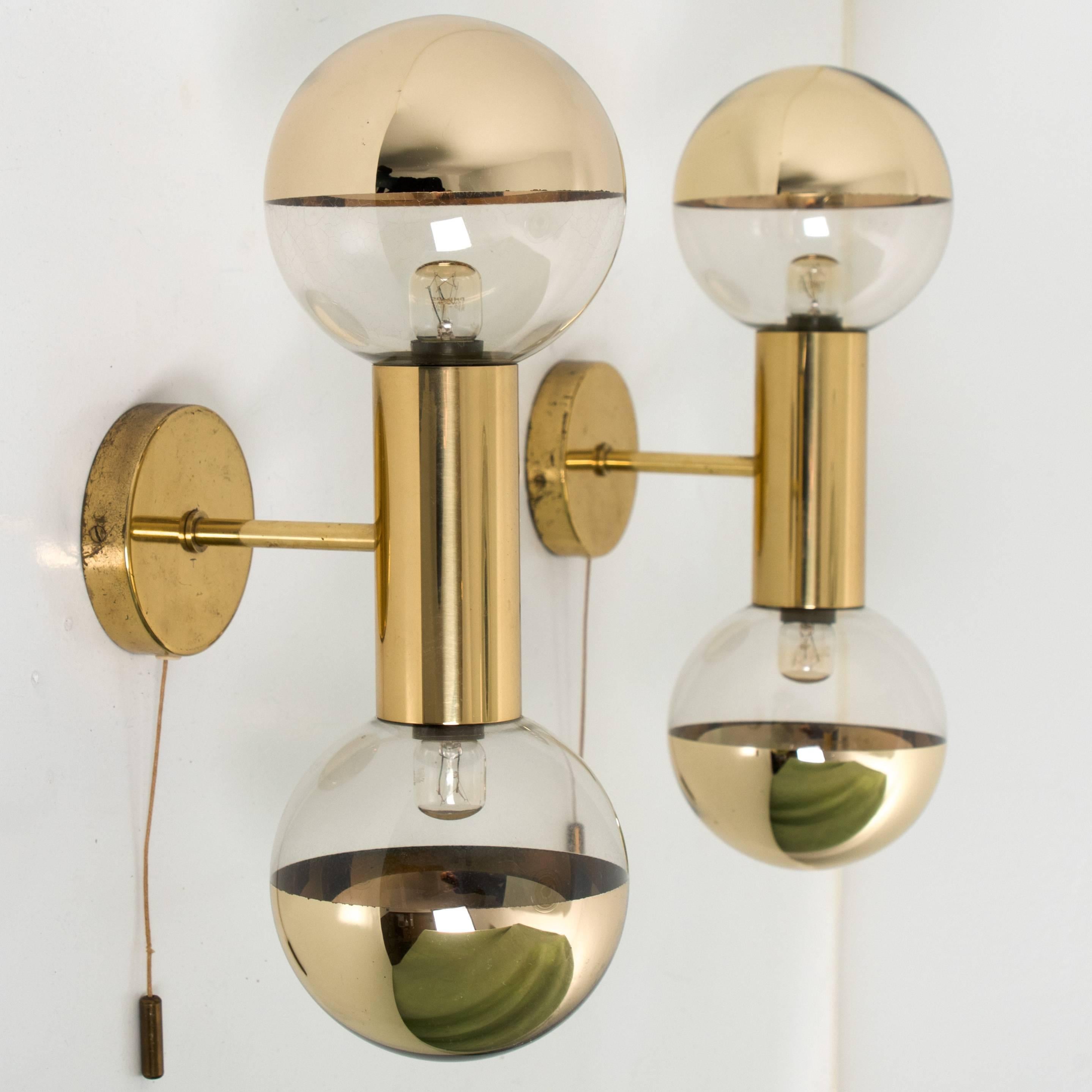 This pair of midcentury wall sconces was designed by Motoko Ishii in the 1970s and later manufactured by Staff in Germany. 

They are made from brass and glass and feature two lights each (two x E14 small bulbs). Heavy quality, cleaned, well-wired