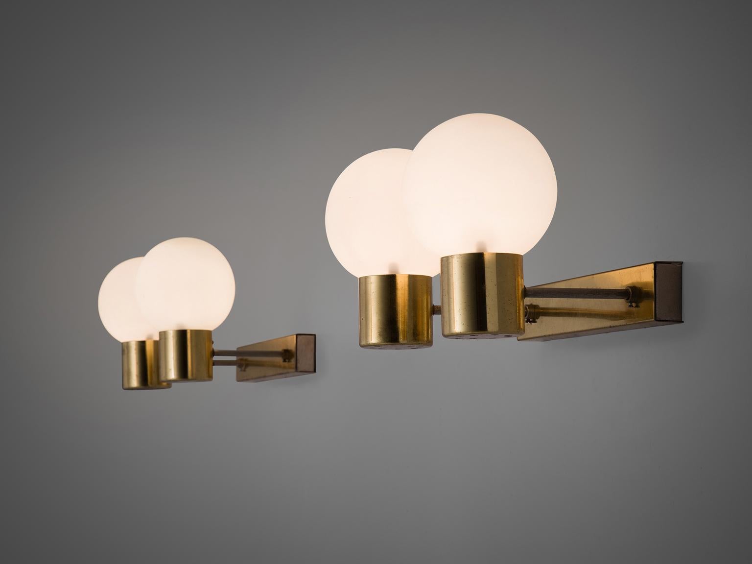 Wall lights in brass and opaline glass, Europe, 1960s. 

Set of 2 solid brass sconces with glass shades with a warm opaline white shade. The lights each have relatively long arms ending in an opaline light bulb. These wall scones have a very natural