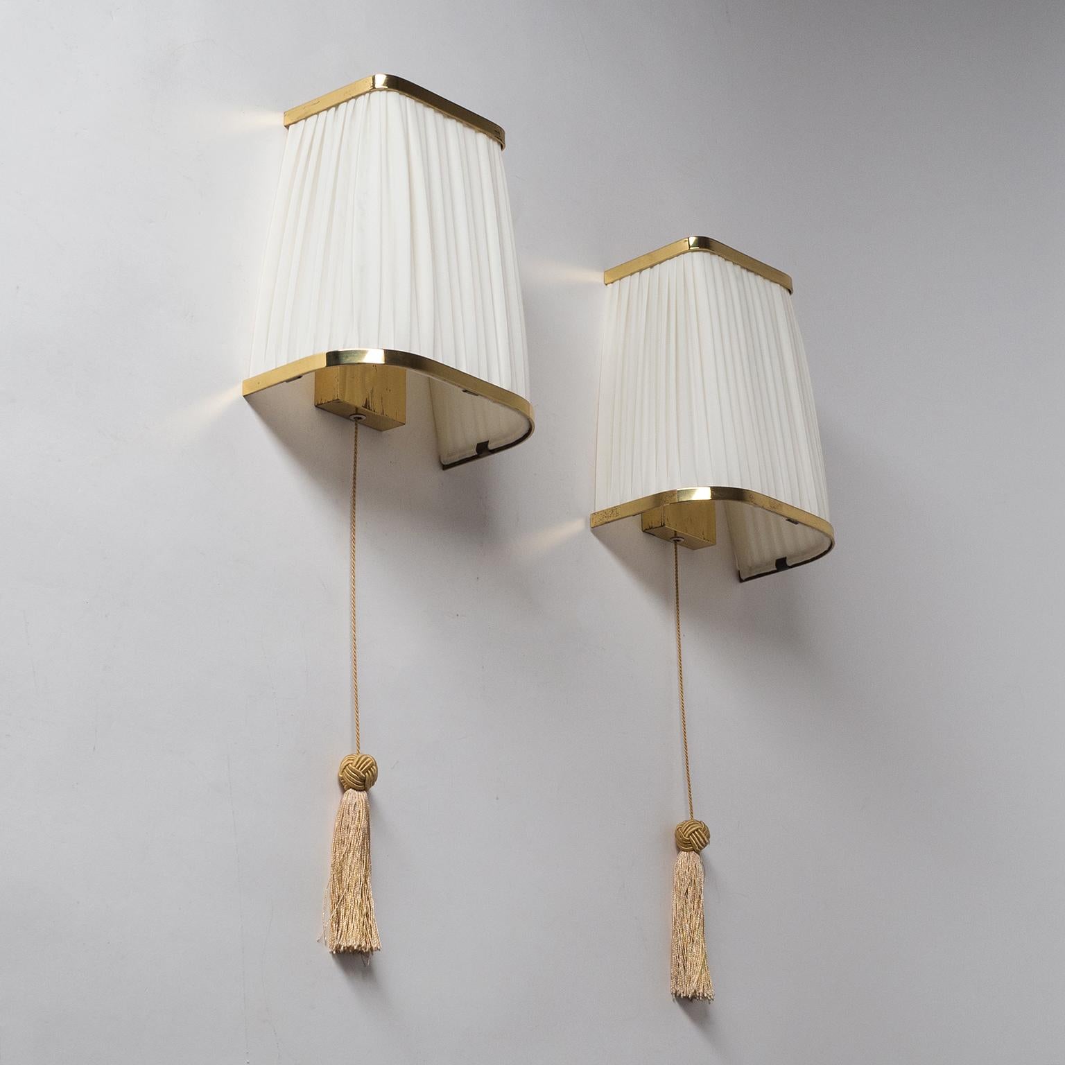Fine pair of brass wall lights with large pleated shades from the 1940s-1950s. One original brass E27 socket with new fabric on the original shades. Height with tassel is 20inches/51cm.
