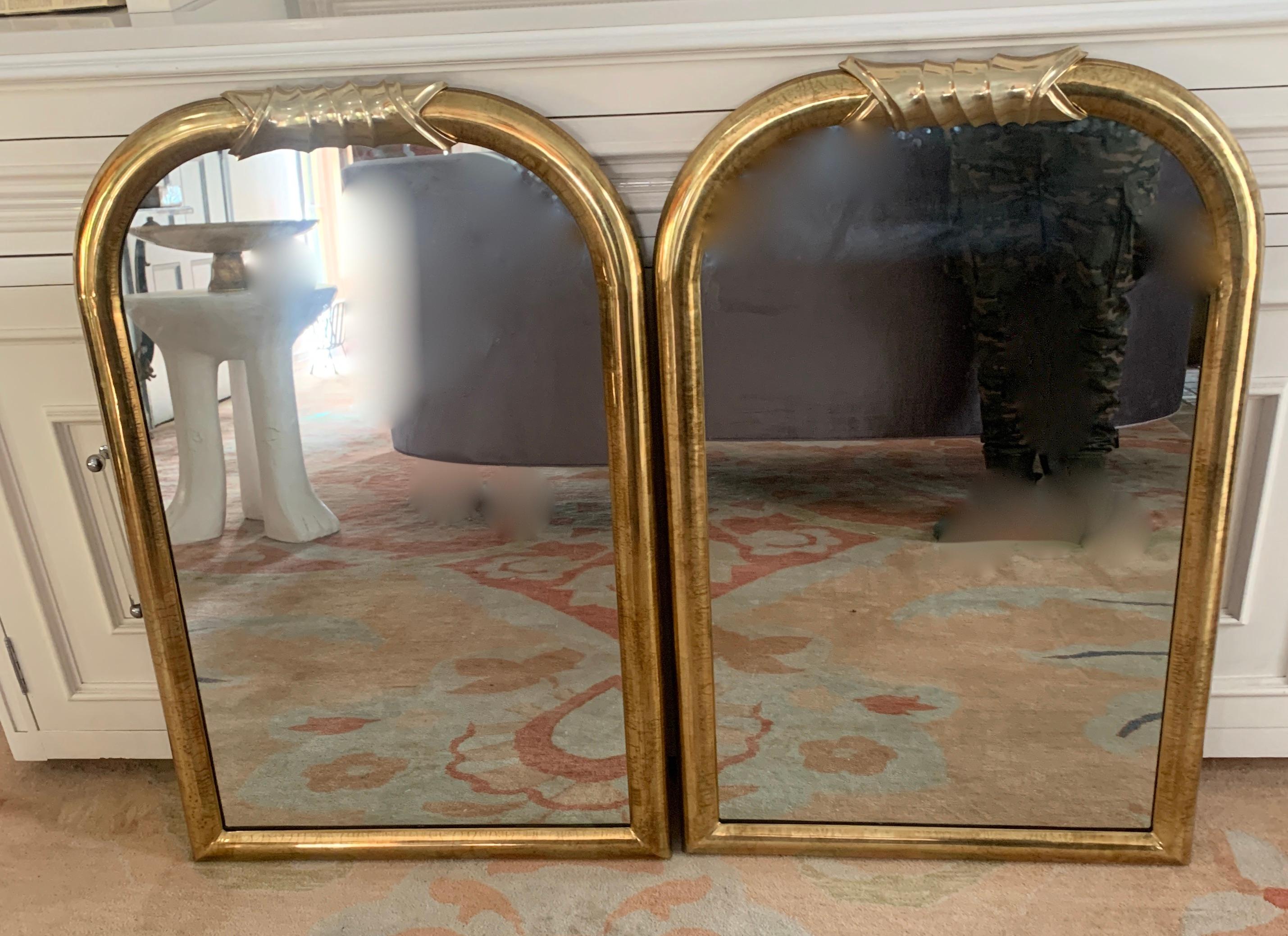 Pair of brass wall mirrors the style of Louis Philippe, a wonderfully designed and constructed modern pair of wall mirrors in brass. The frame has a simple rounded perimeter, and atop comes together in an architectural twist. both have velvet backs