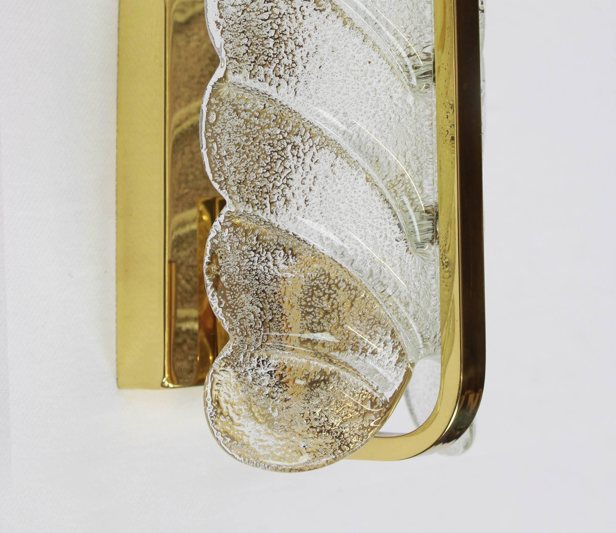 Apliques de pared muy glamurosos diseñados por Carl Fagerlund para Orrefors glass, fabricados a mediados de siglo, hacia 1960-1969. Cada candelabro presenta un marco de latón pulido con una hoja de cristal de Murano que tiene un relieve esmerilado
