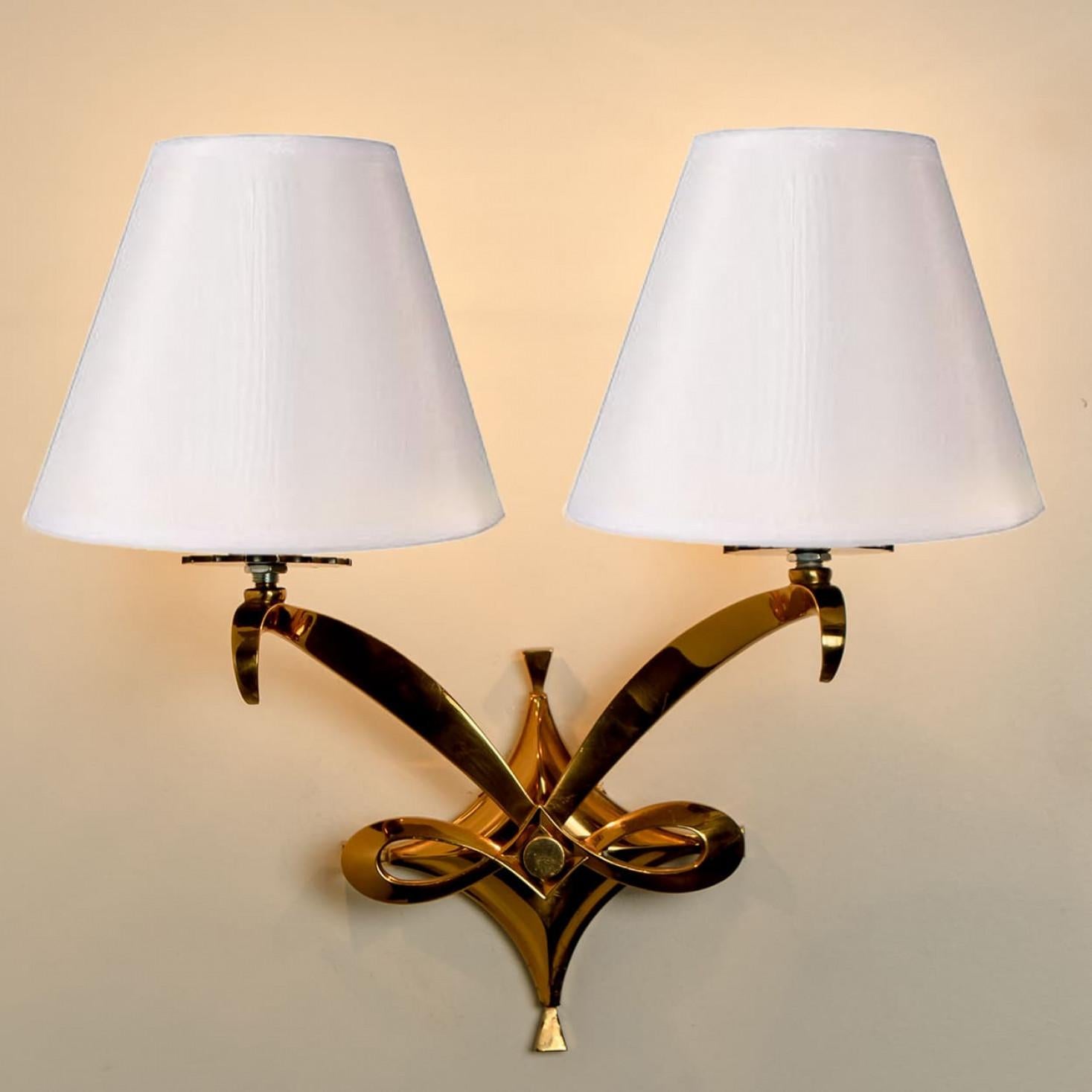 Apliques Leleu de latón real. Cada luminaria consta de varillas curvadas doradas, con una pantalla blanca encima. Montado en un marco de latón dorado. Las varillas refractan la luz maravillosamente. Disponemos de múltiples opciones en cuanto a