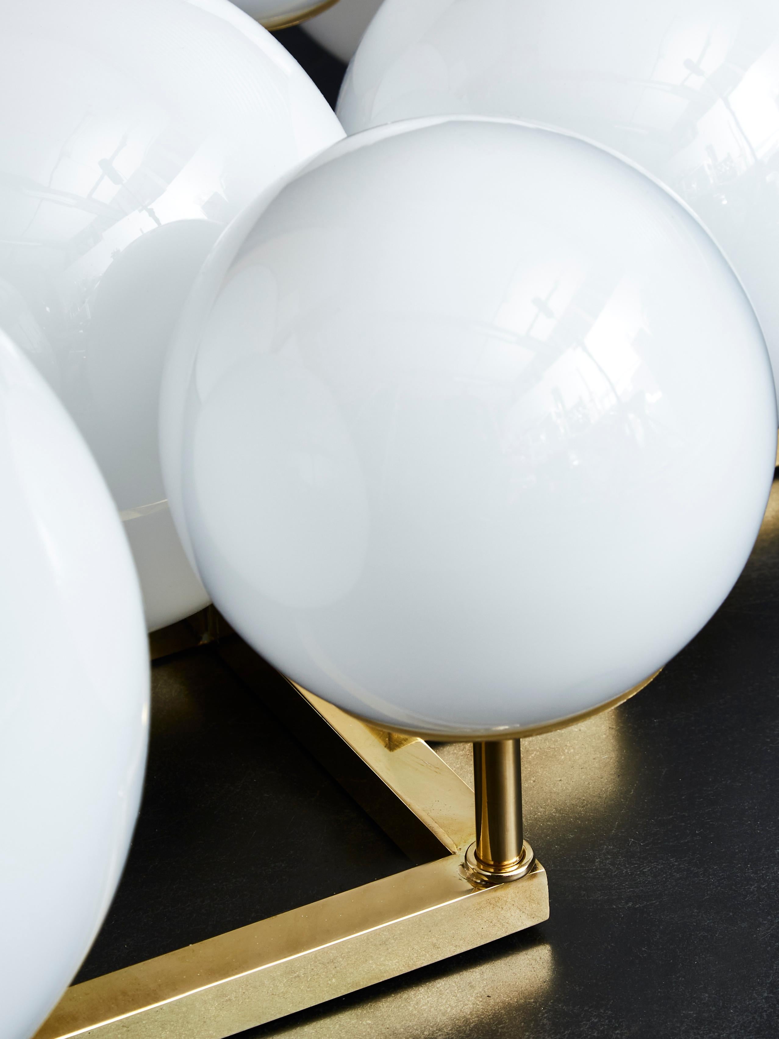 Modern Pair of Brass Wall Sconces with Different Sized White Glass Globes For Sale