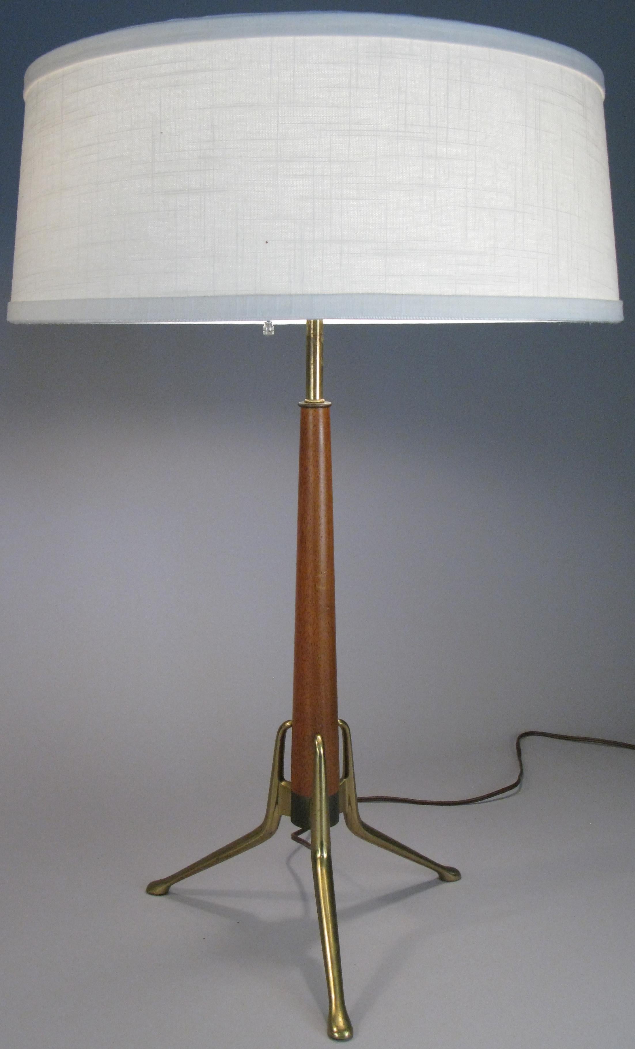 A stunning matched pair of 1950s table lamps designed by Gerald Thurston for Lightolier. Made with a tapered walnut stem raised on a brass base with three legs. These have Lightolier's signature triple socket fitting, giving the option of having